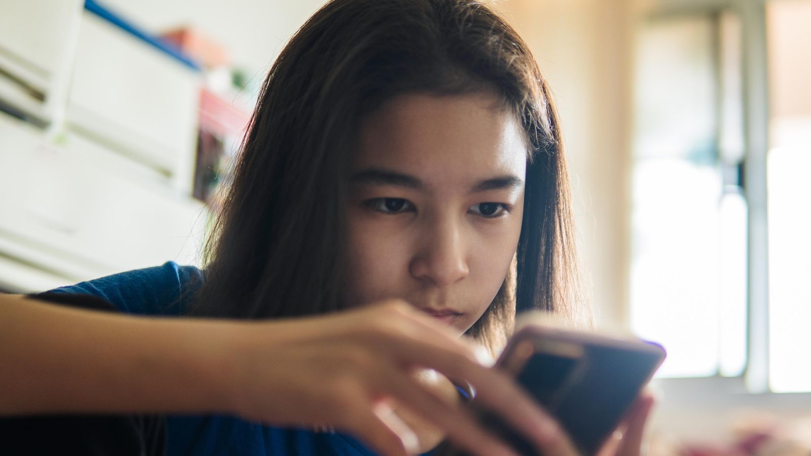 Adolescent utilitzant un telèfon per a entrar en xarxes socials