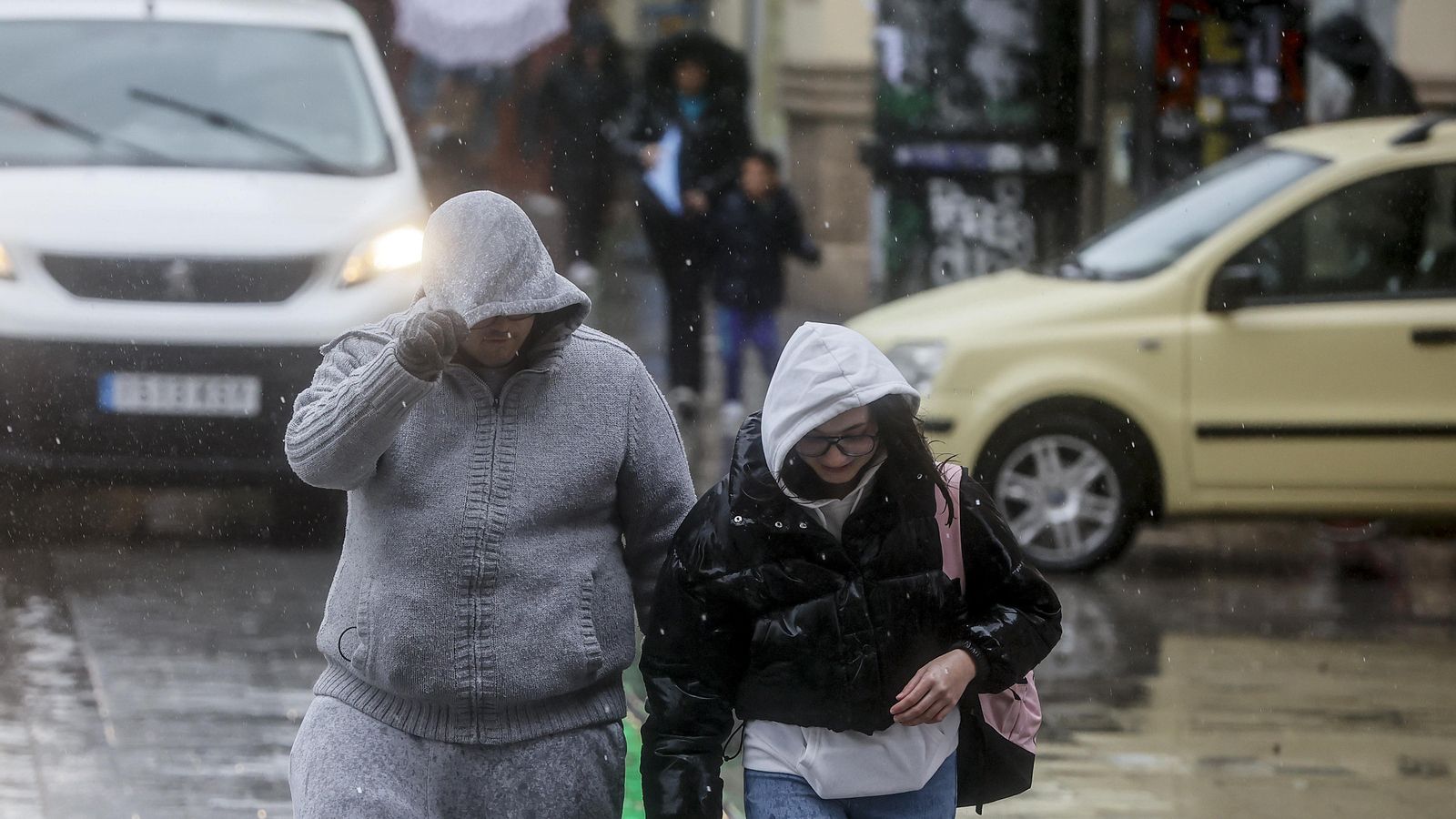Dos persones es protegeixen amb la caputxa de la pluja i el vent a València en una imatge d'arxiu