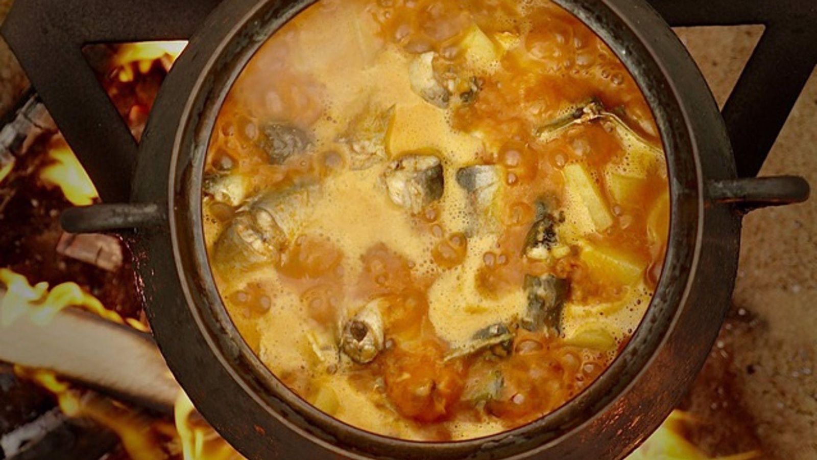 Un perol d'allipebre al foc, on s'aprecien els troços d'anguila i creïlla