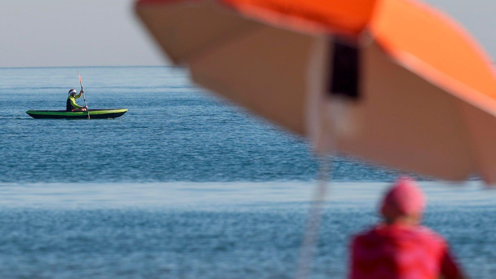 Un home amb barret de Pare Noel navega en caiac a la platja de la Malvarosa de València aquest dissabte