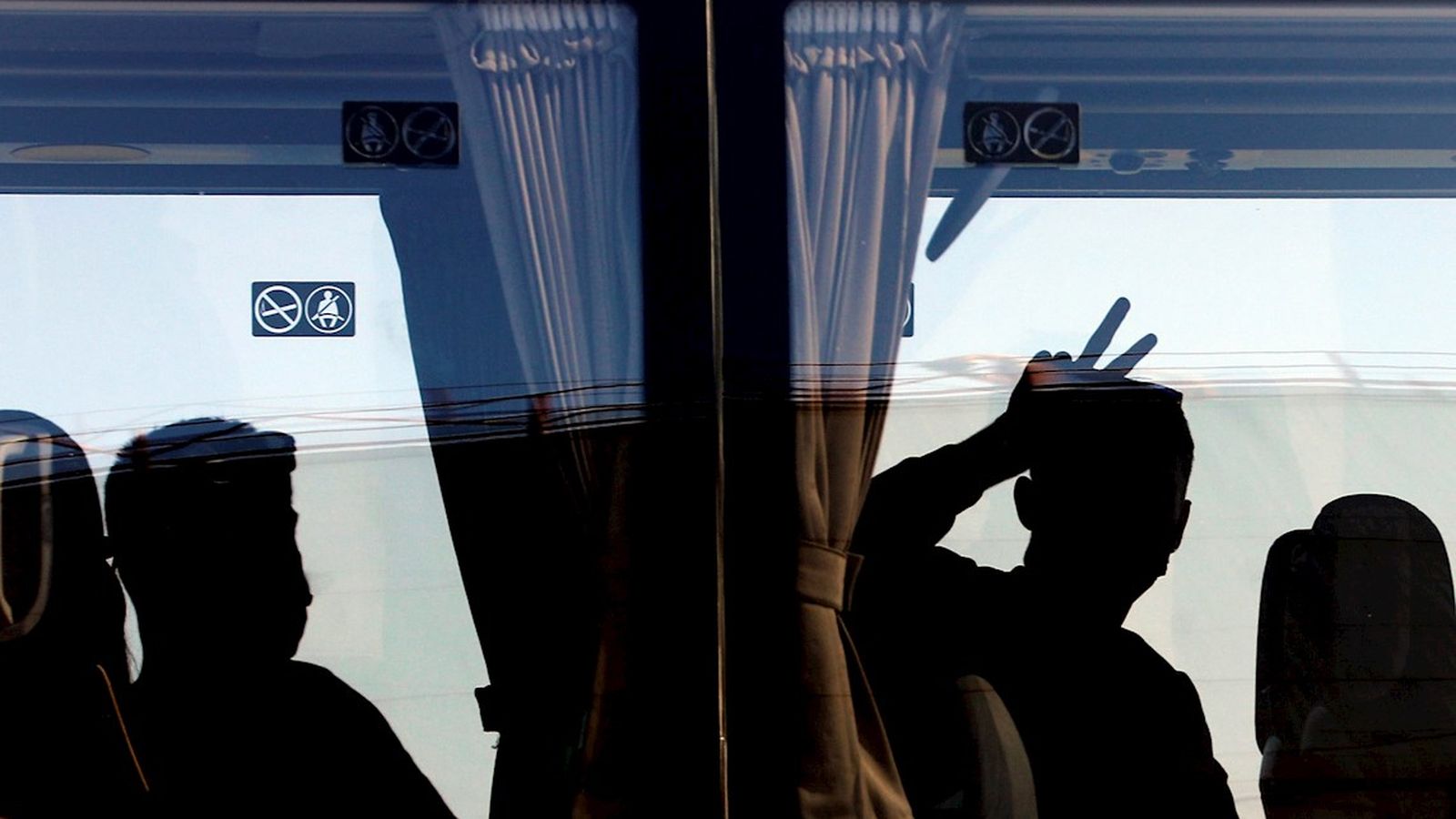 Una persona saluda des de l'autobús després de desembarcar del ferri en el qual viatjaven 118 estudiants que havien sigut confinats en un hotel de Mallorca després del macrobrot detectat a l'illa.