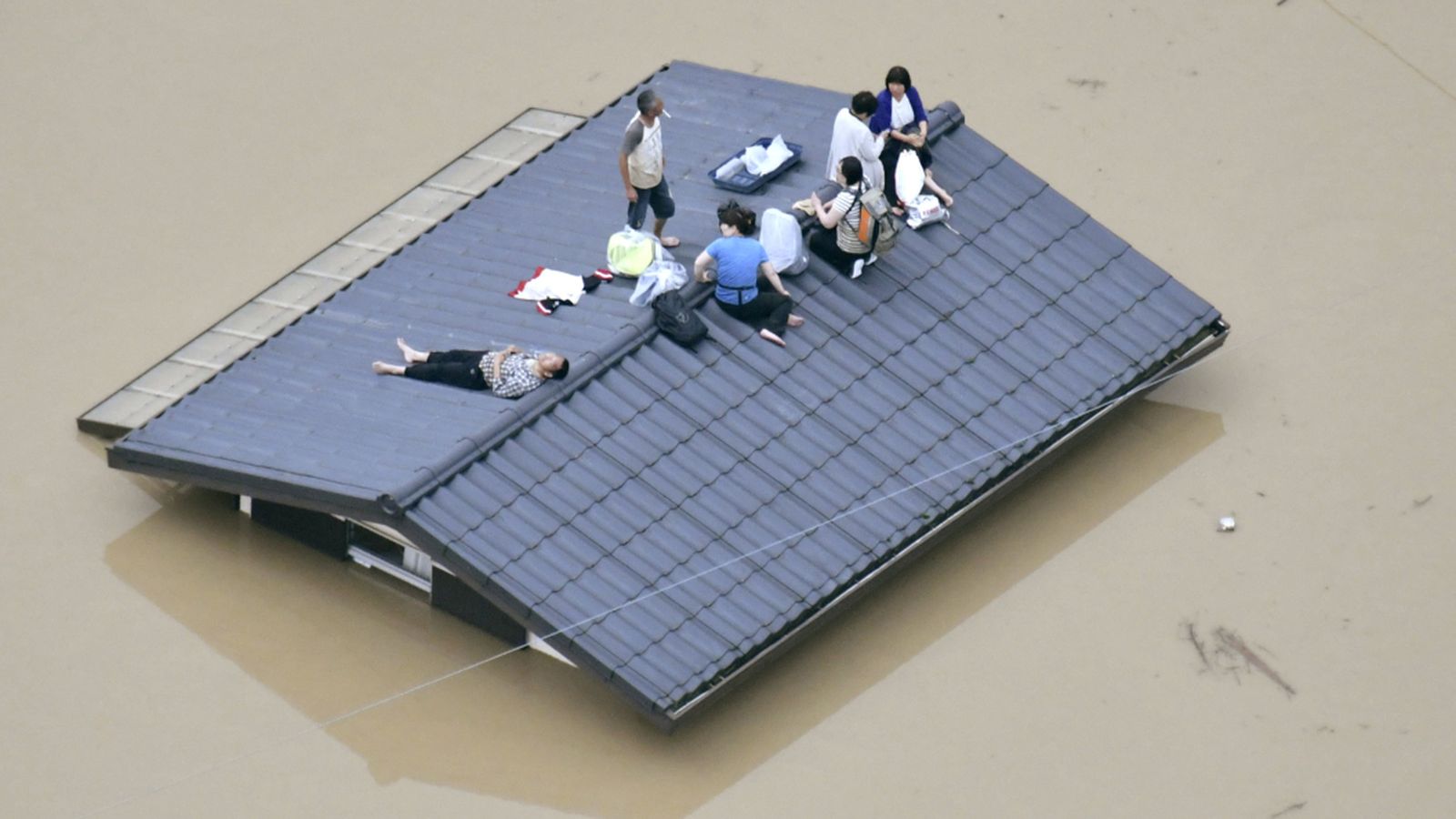 Residents locals en el sostre d'una casa submergida en una zona inundada mentre esperen un rescat en Kurashiki, al sud de Japó