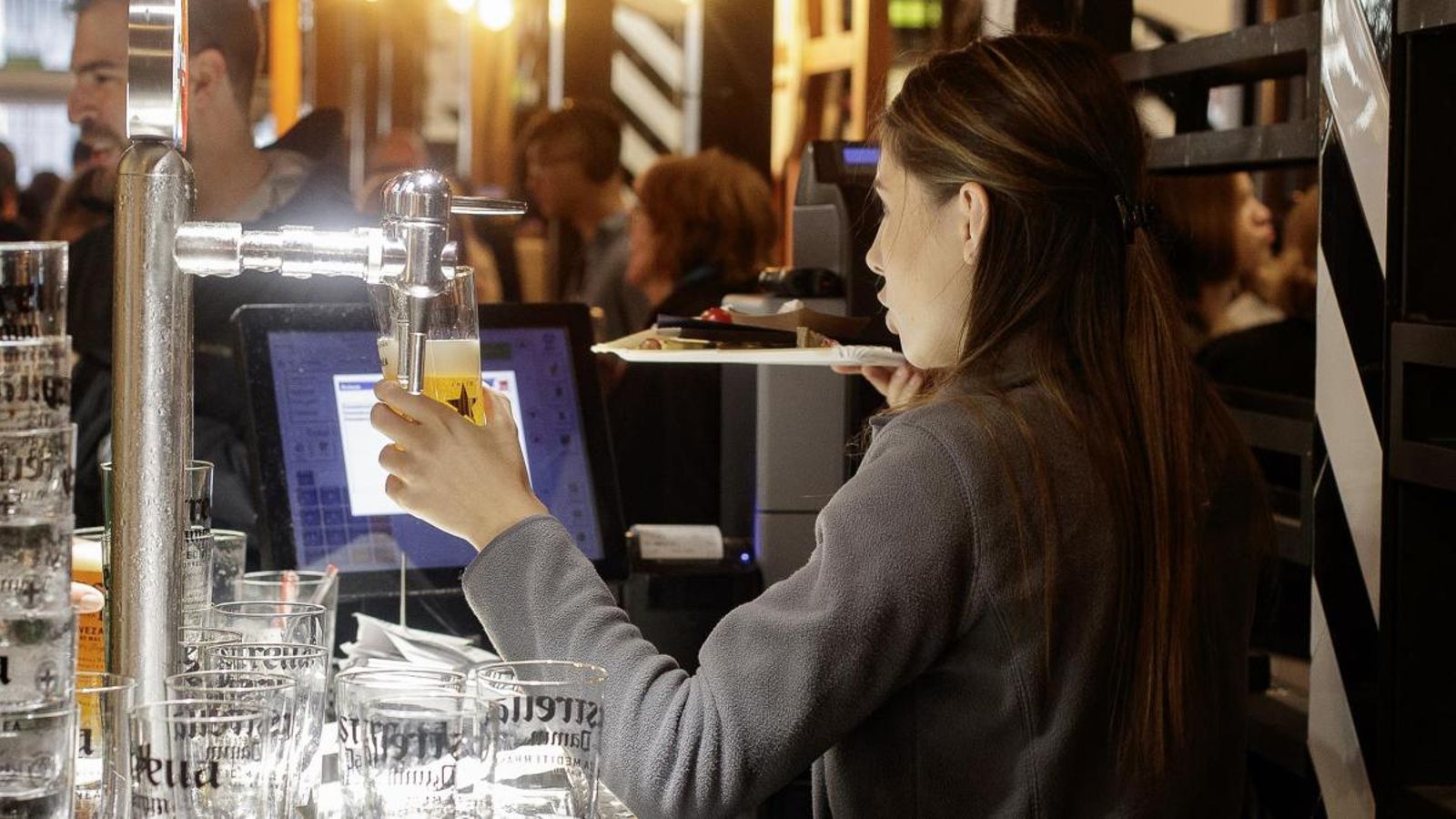 Una cambrera serveix una cervesa en un bar