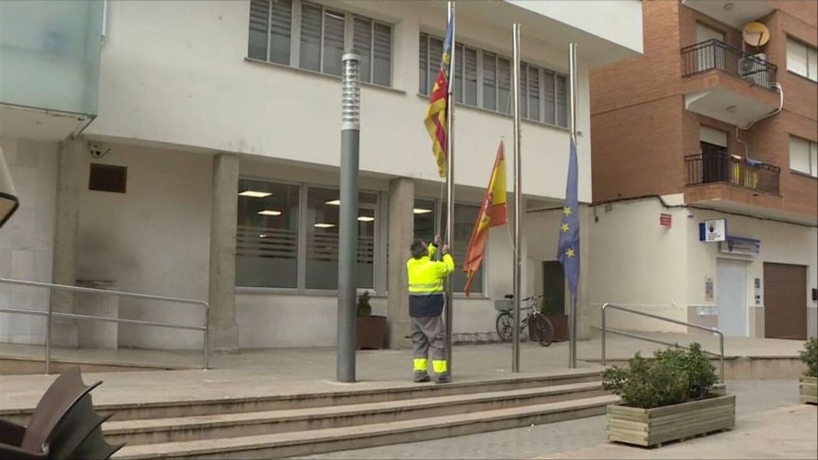 Un operari municipal abaixa les banderes de l'Ajuntament de Vilamarxant, en senyal de dol oficial, pel pressumpte crim del nadó d'onze mesos