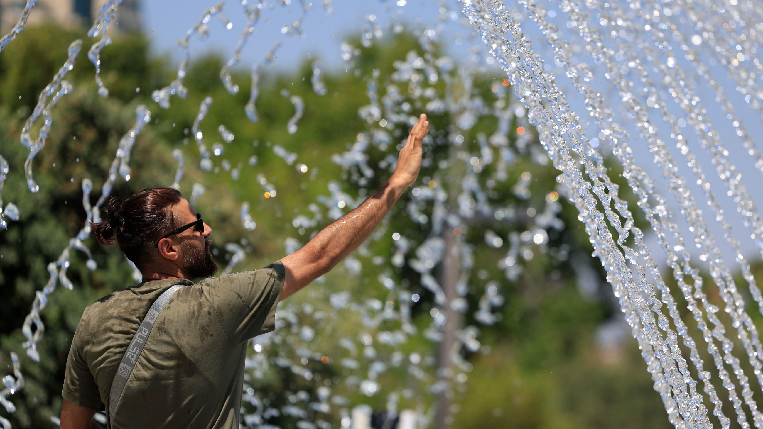 Un home es refresca en una font a València Un home es refresca en una font a València