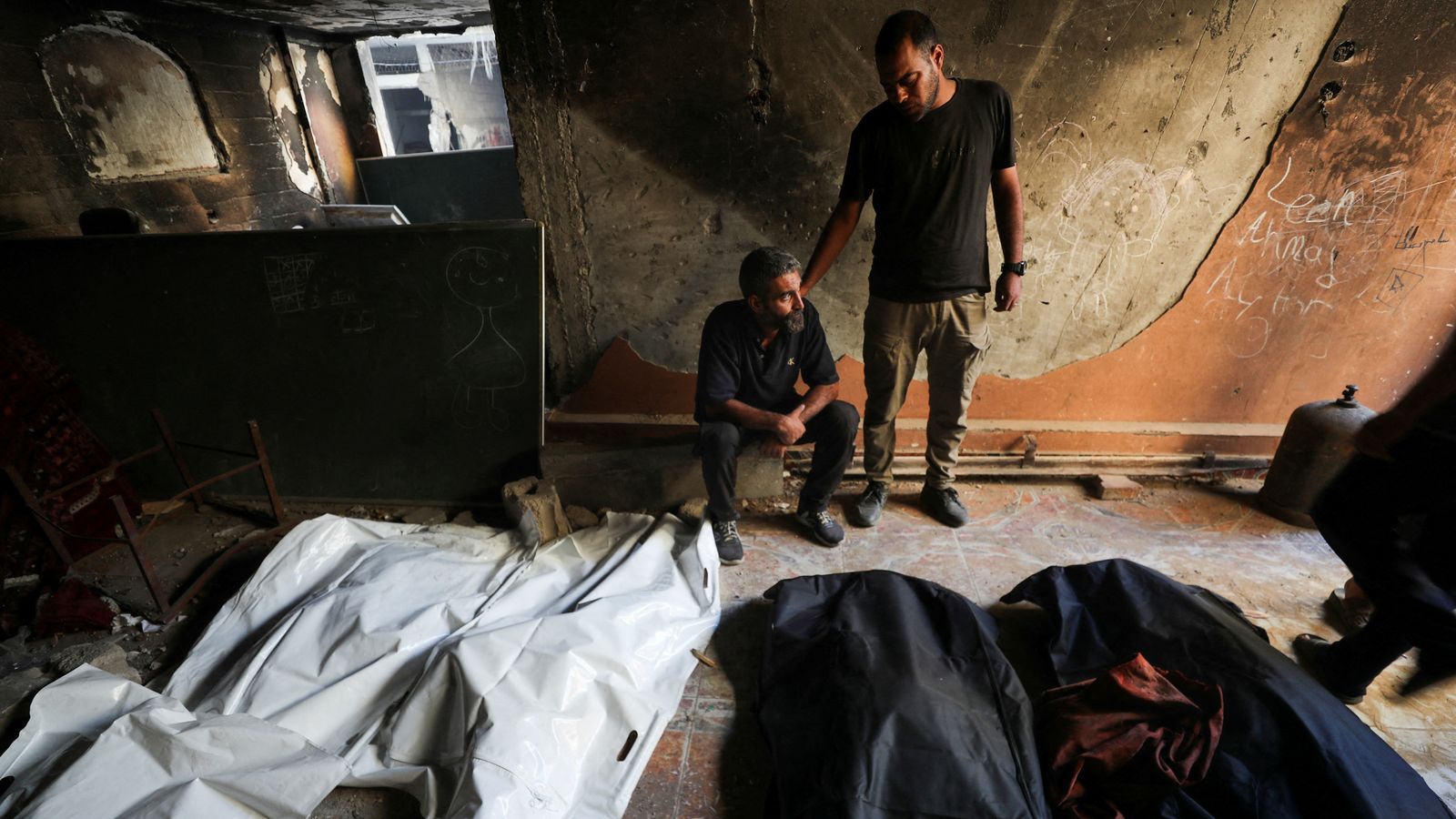 Dos homes contemplen cadàvers després dels bombardejos israelians a la Ciutat de Gaza