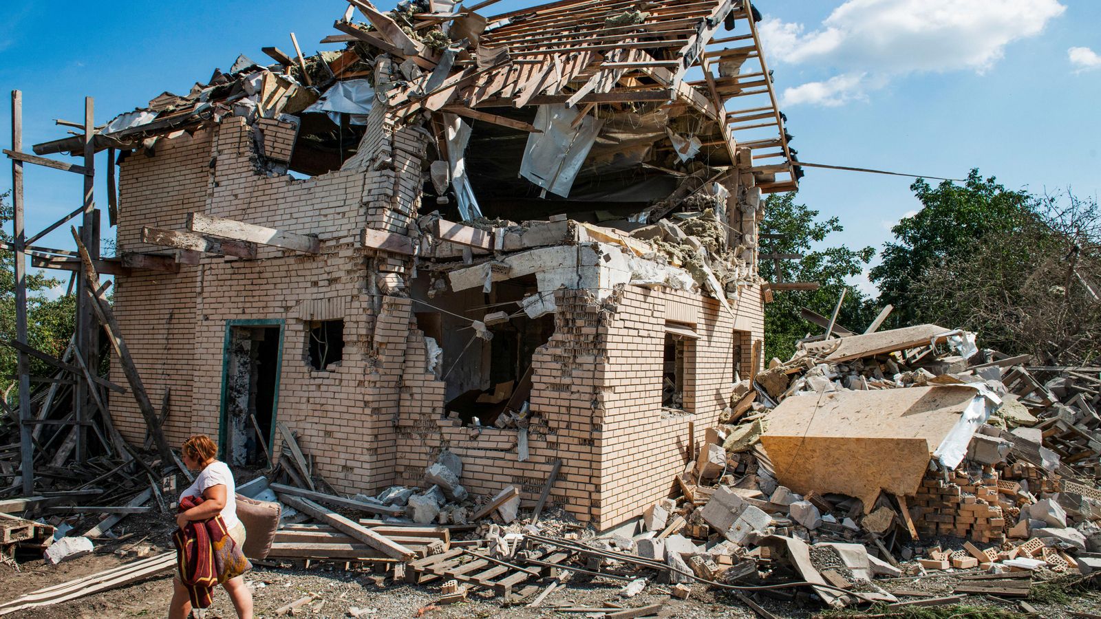 Una dona porta pertinences de les ruïnes de la seua casa destruïdes en un atac amb míssils russos a la regió de Kíiv, Ucraïna