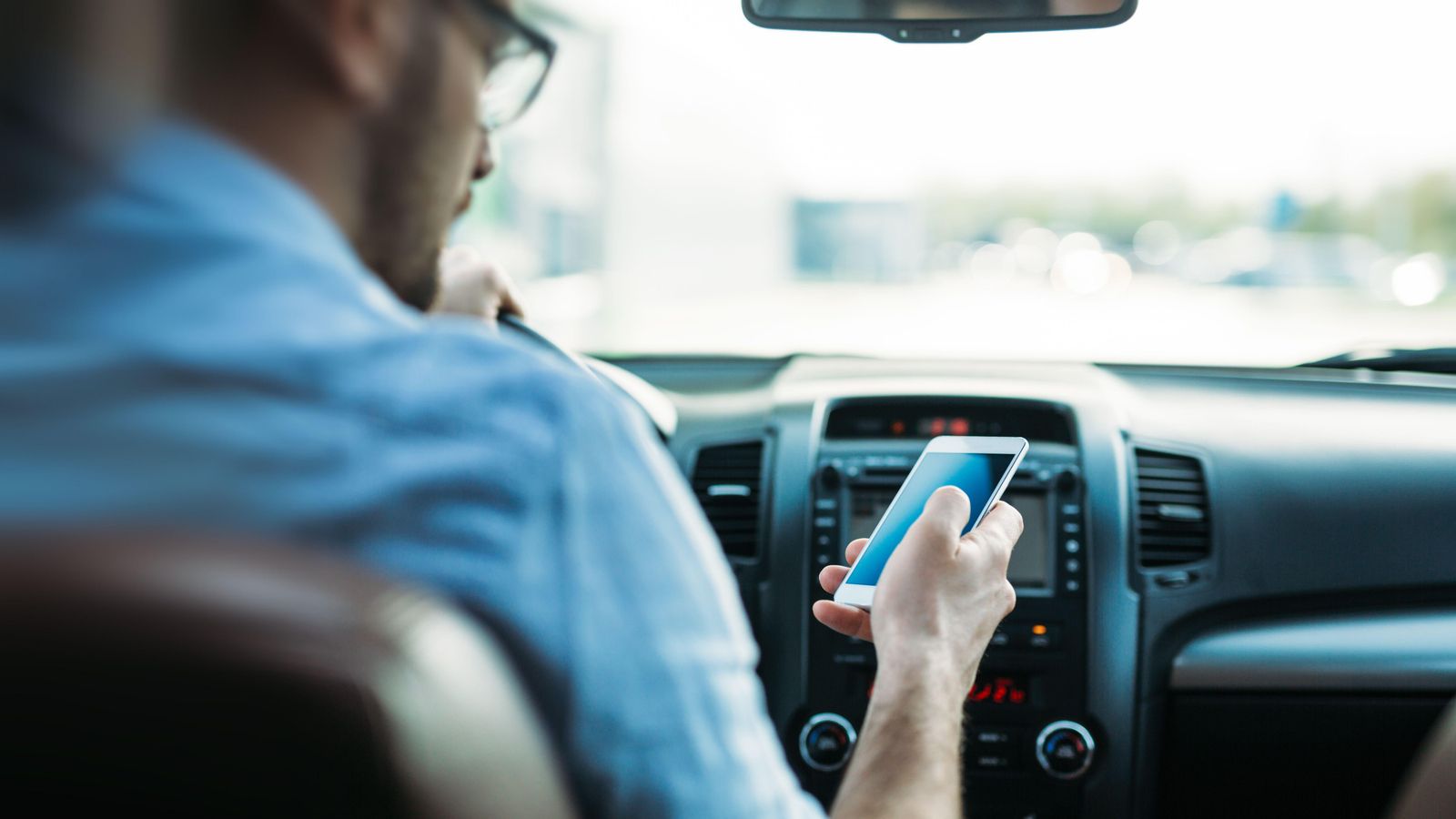 Un conductor mira el seu telèfon móvil