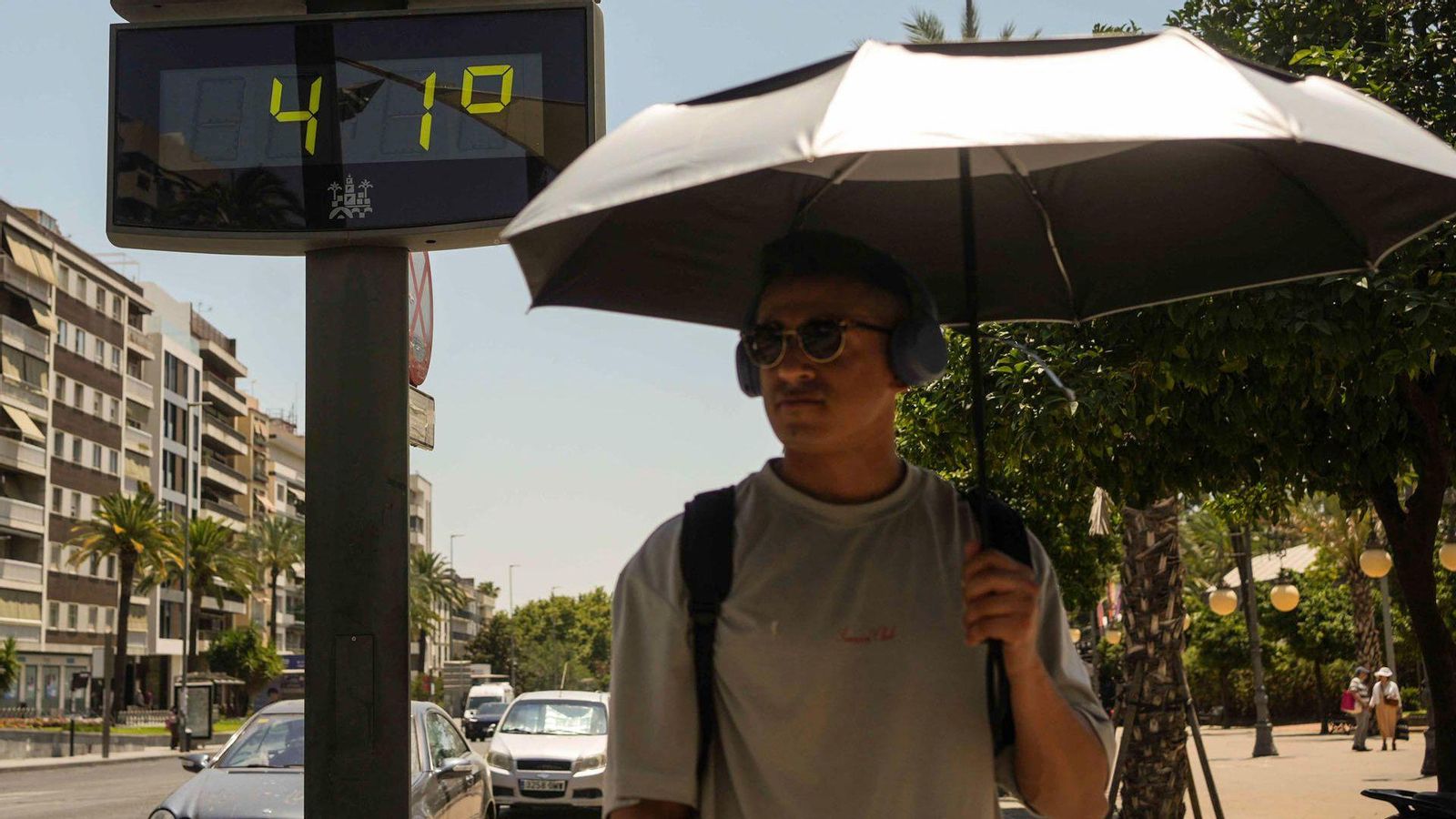 Un home cobert amb un paraigua passa al costat d'un termòmetre