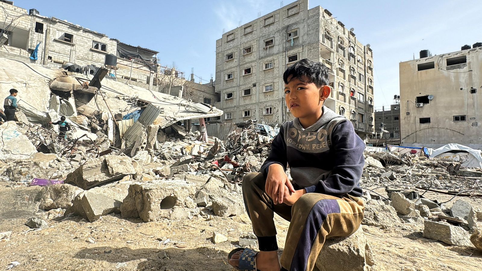 Un xiquet palestí descansa sobre els enderrocs d'un habitatge de Rafah, destruït per un bombardeig israelià