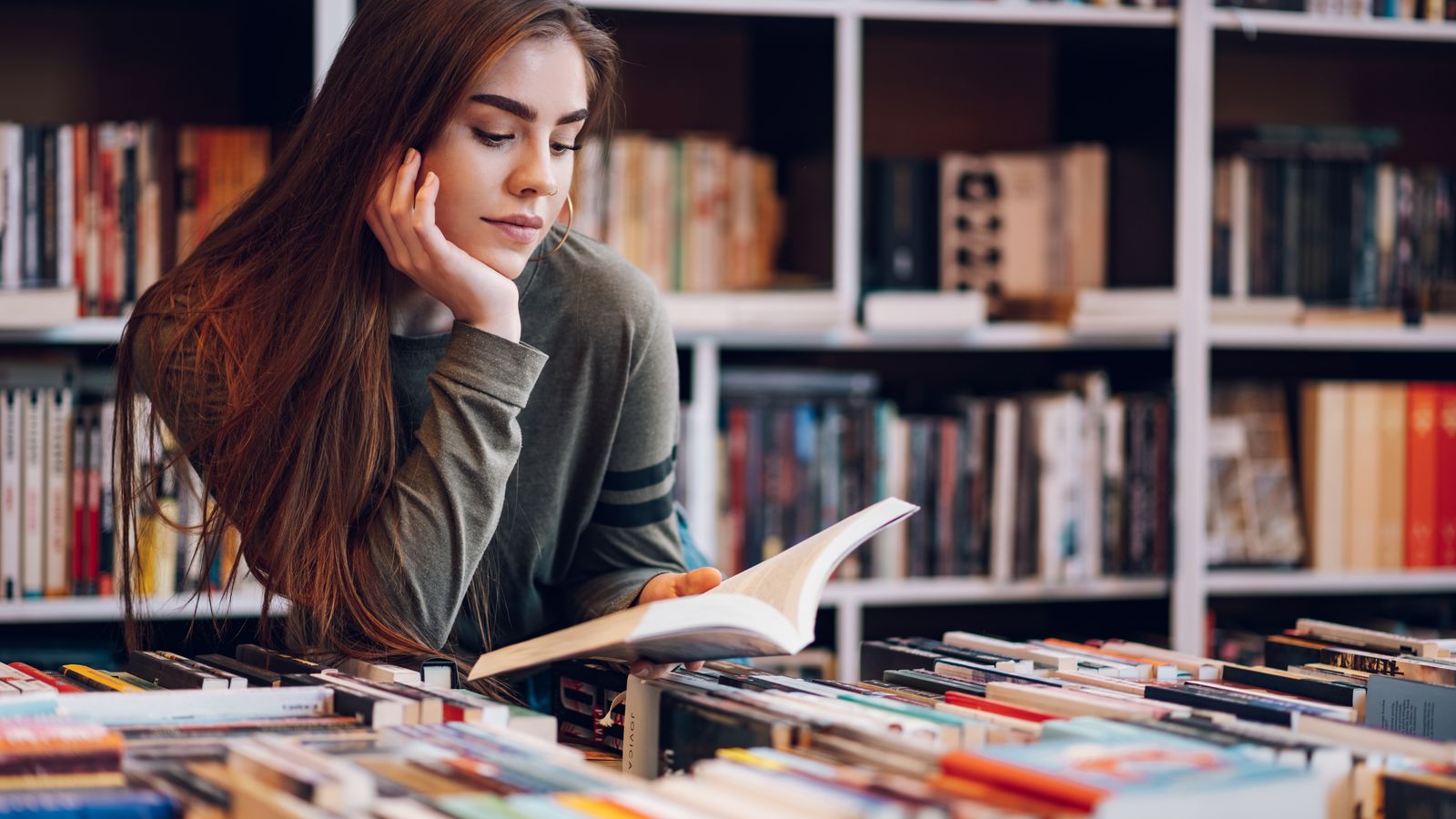 Una jove llig un llibre en una llibreria