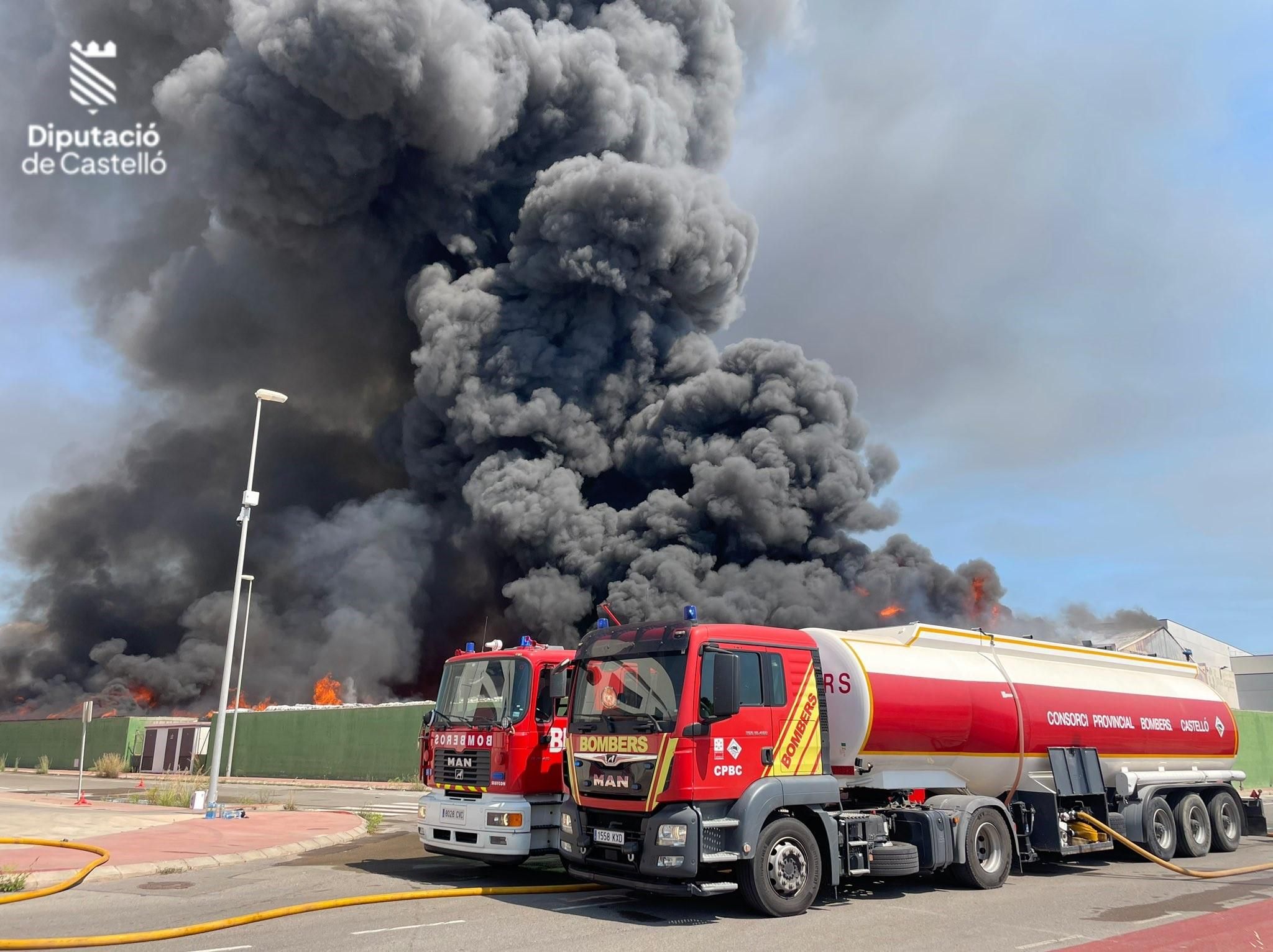 Un camió amb un tanc d'aigua dels bombers treballa a la nau cremada