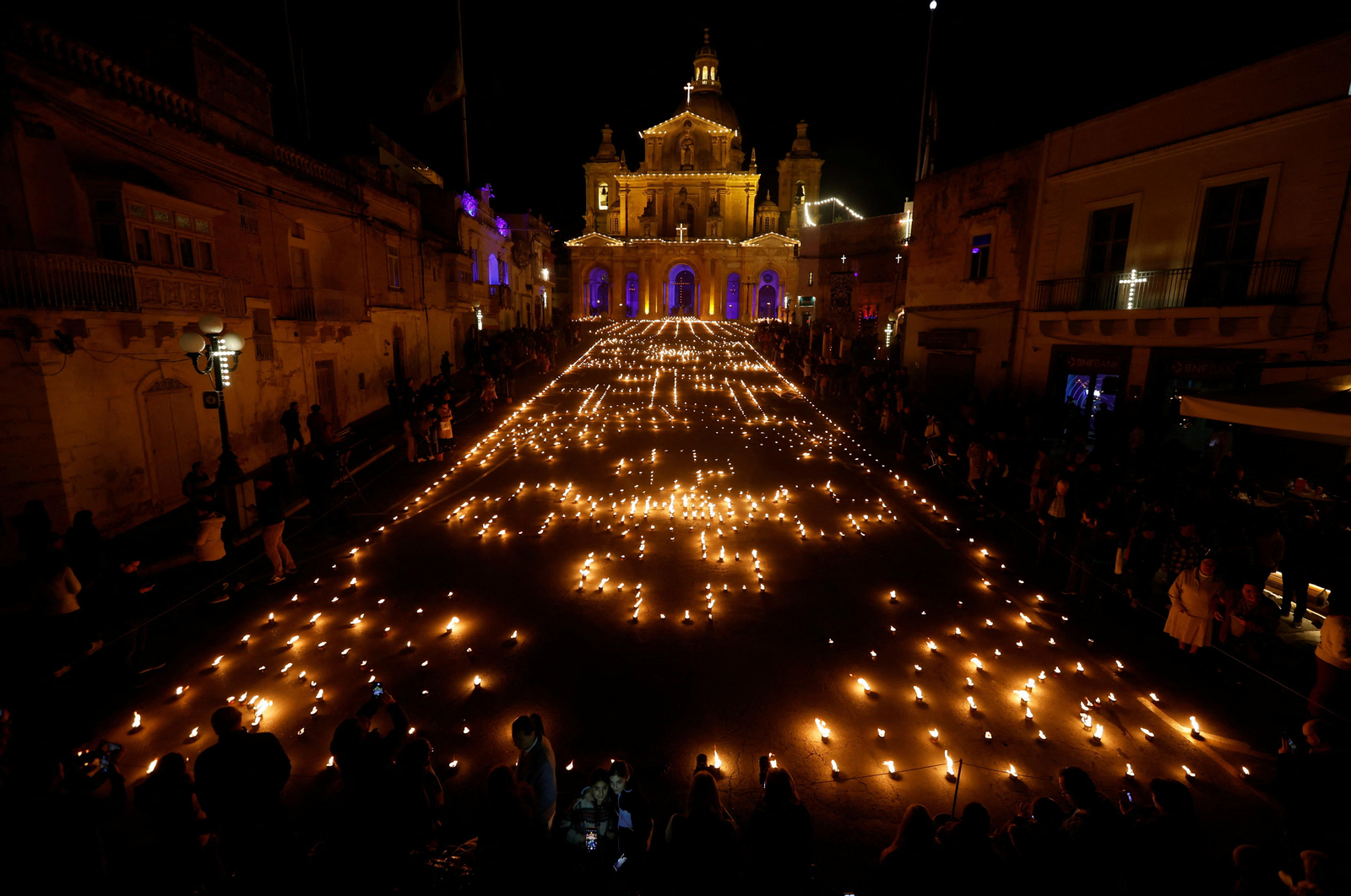 Les torxes i les espelmes enceses omplin la plaça davant l'església de Sant Nicolau el Dijous Sant (6 d'abril de 2023)