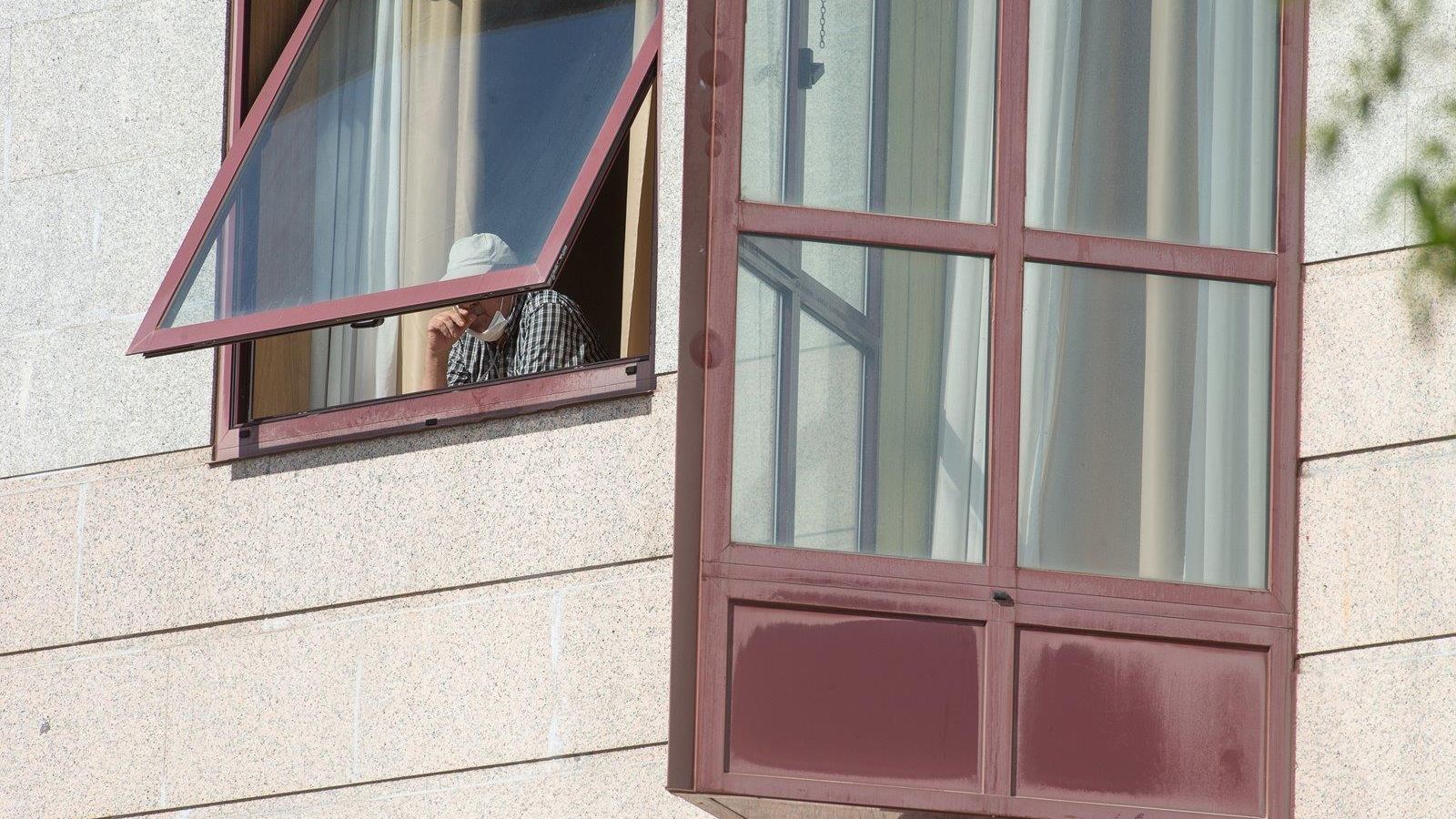Un ancià trau el cap per la finestra d'una residència