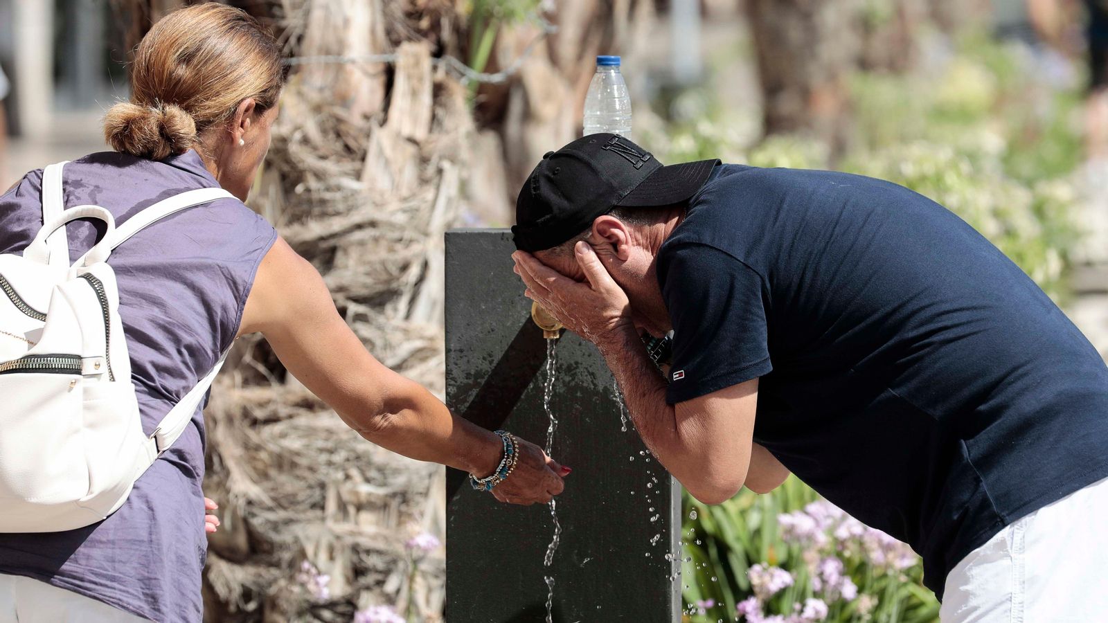 Dues persones es refresquen en una font del centre de València