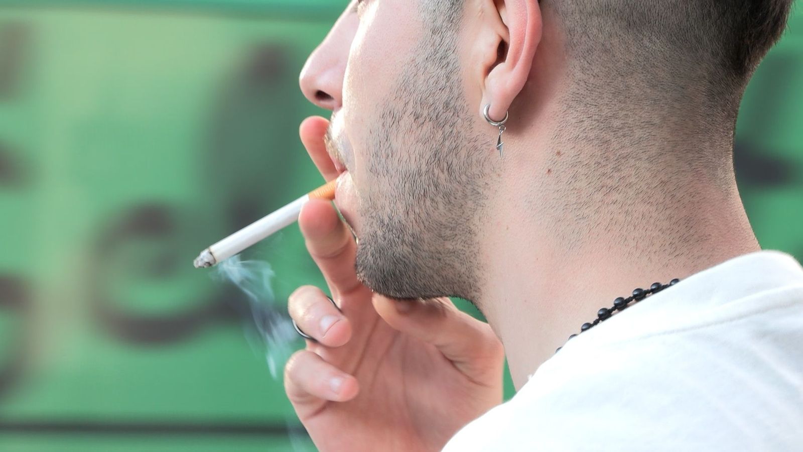 Un jove fuma un cigarret al carrer