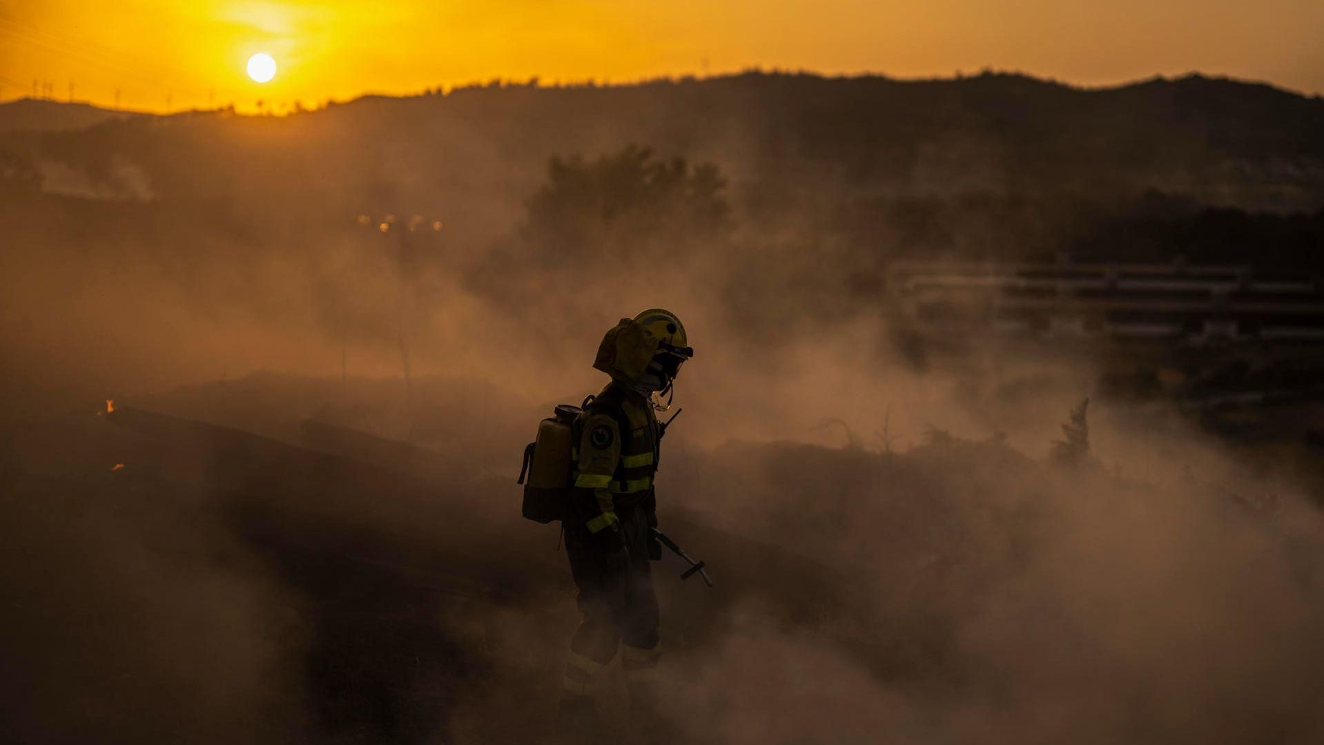 Un bomber avança entre el fum generat per l'incendi declarat a Monterrei, a la província d'Ourense