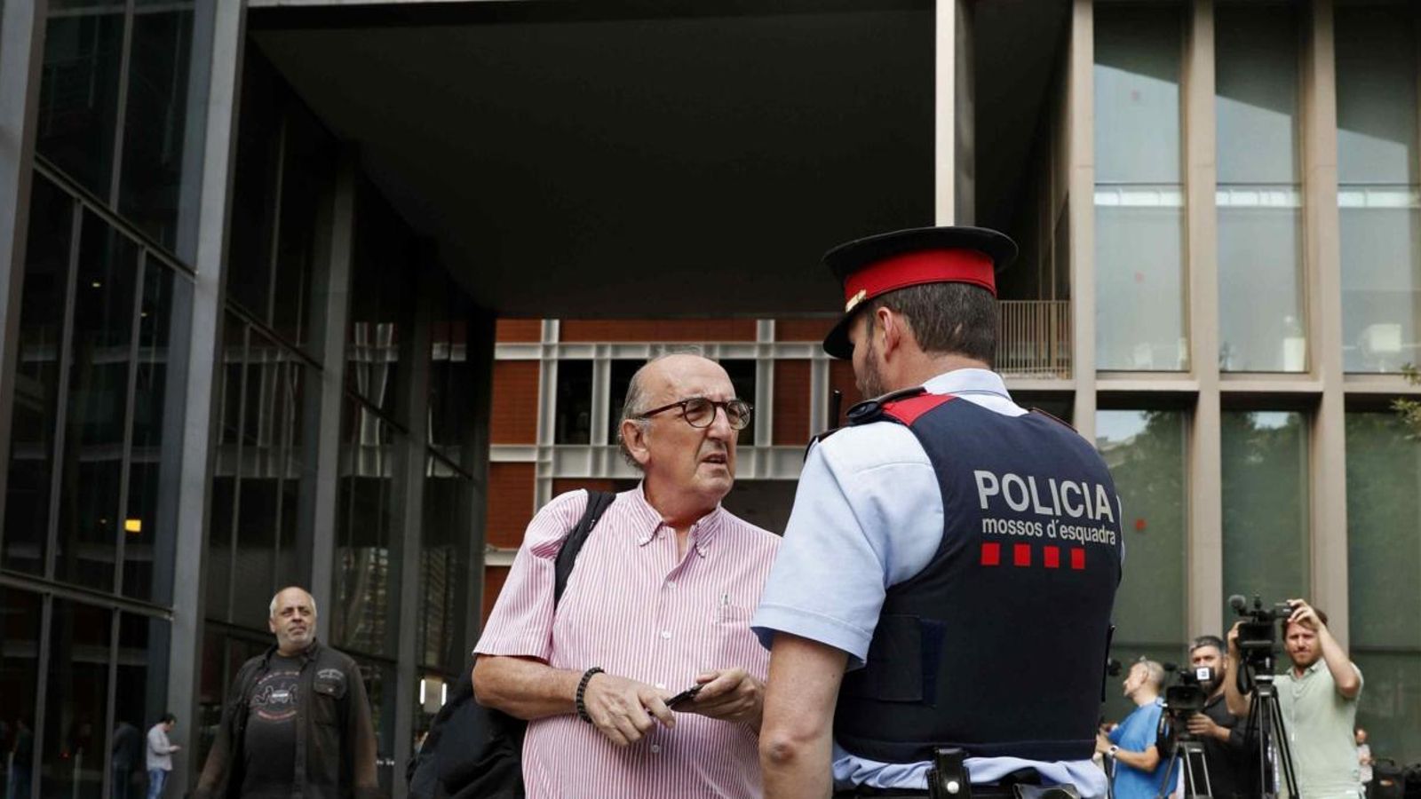 El president de Mediapro, Jaume Roures, parla amb un mosso d'esquadra davant la seu de la seua companya.