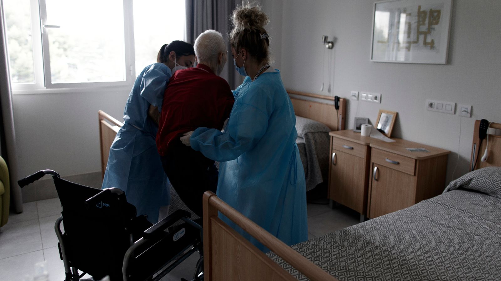 Dos treballadores ajuden a un resident d'una residència