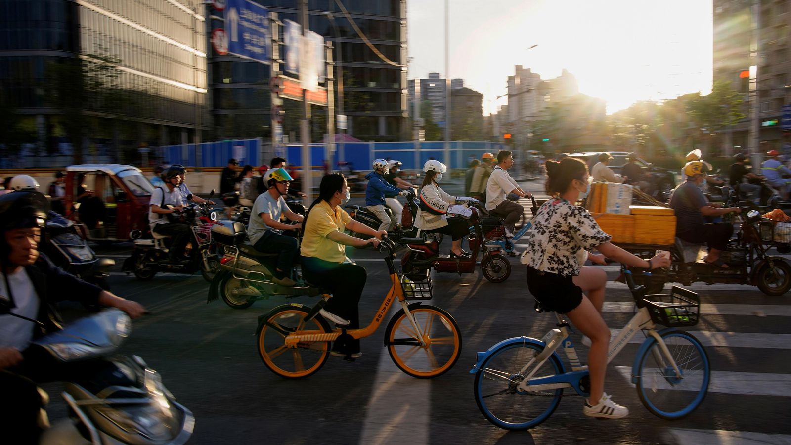 Diverses persones circulen en bicicleta i motocicleta per un carrer de la ciutat xinesa de Xangai