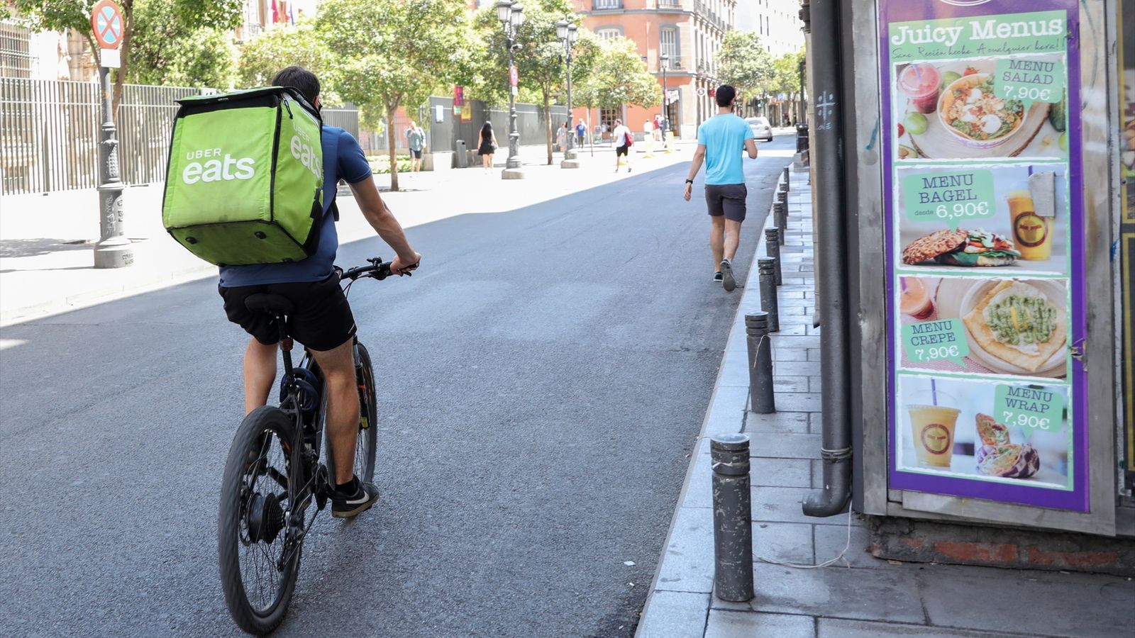 Un repartidor de l'empresa Uber Eats en bicicleta per un carrer del centre de Madrid.