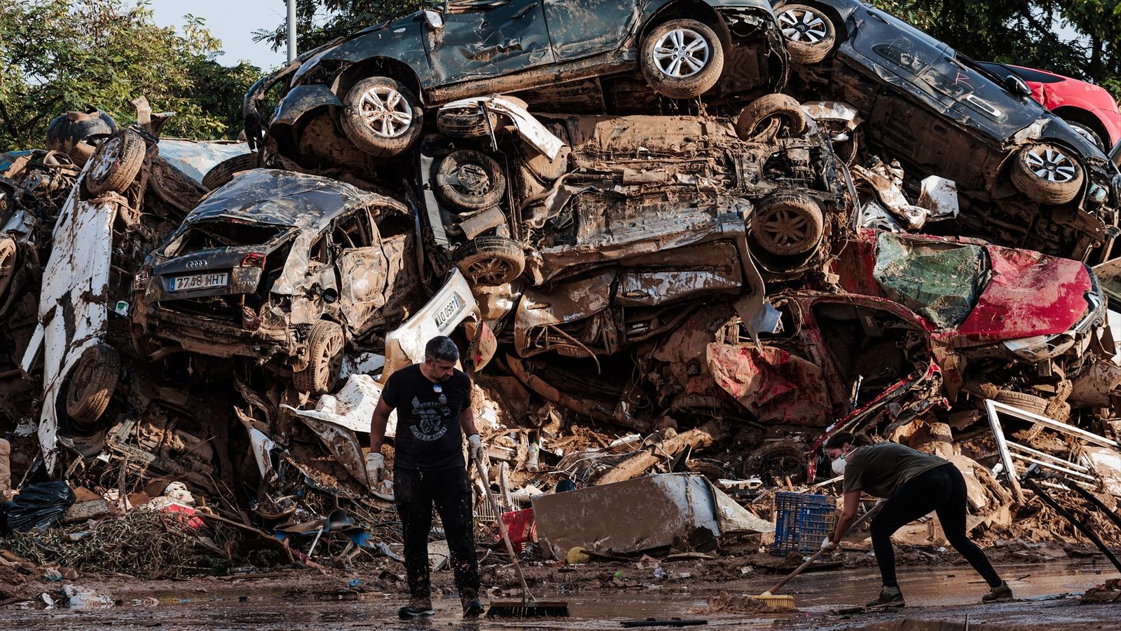 Voluntaris netegen davant de diversos cotxes apilats a Alfafar