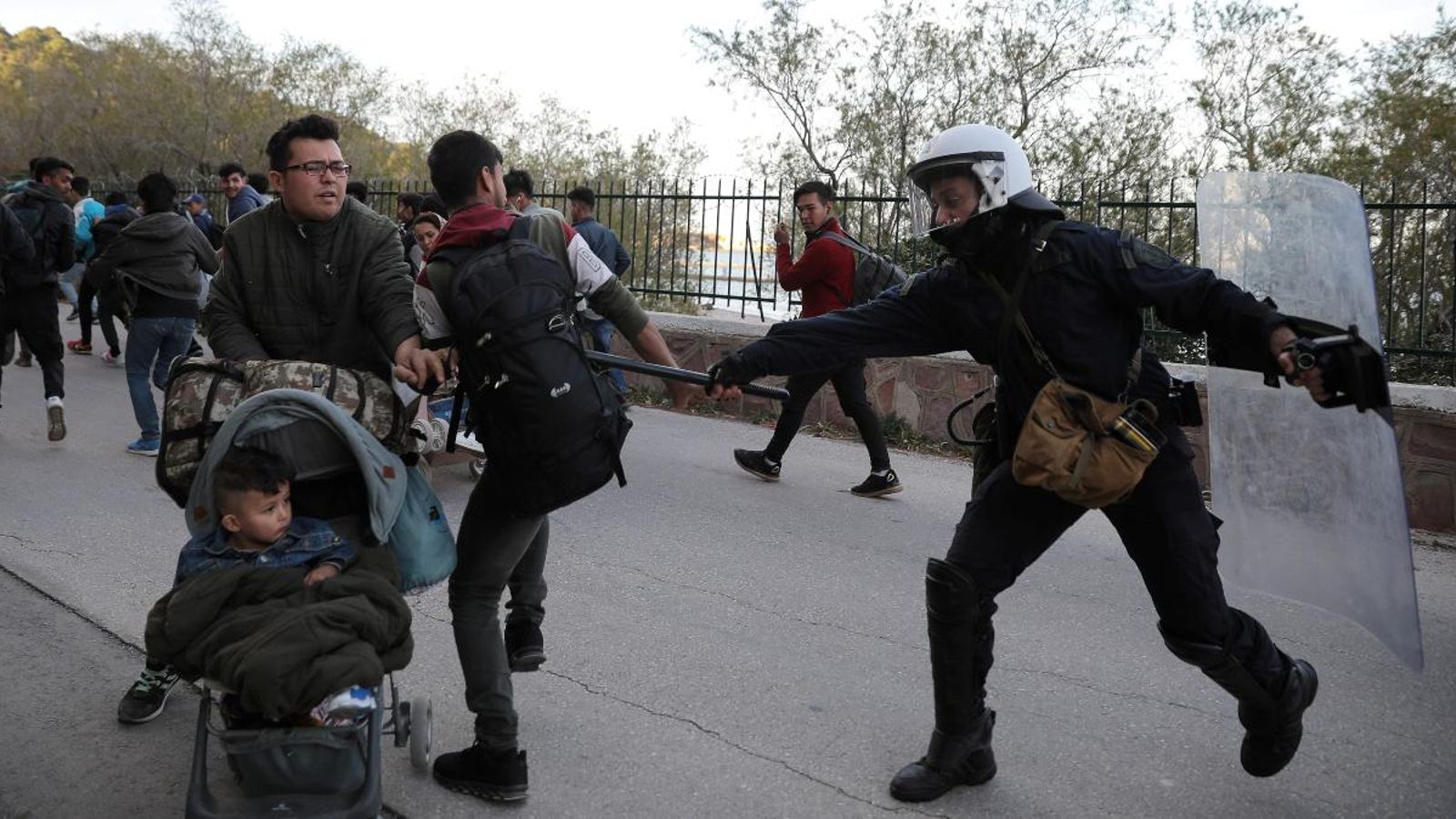 Un policia antidisturbis colpeja un jove mentre intenten dispersar un grup de migrants fora del port de Mitilene, a Grècia, aquest 3 de març