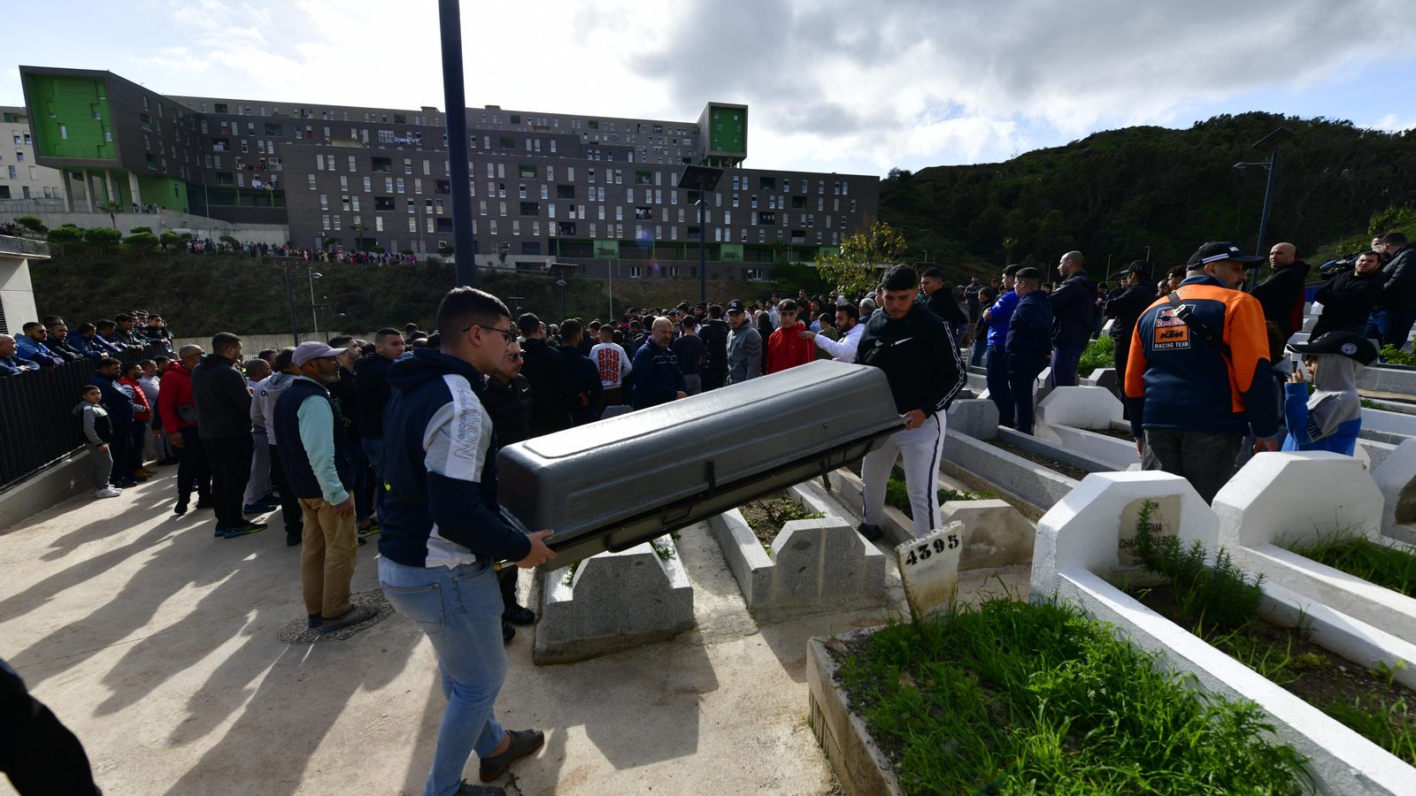 Dues persones transporten el fèretre amb les restes del xiquet de huit anys per al seu enterrament en el cementeri musulmà Sidi Embarek, a Ceuta
