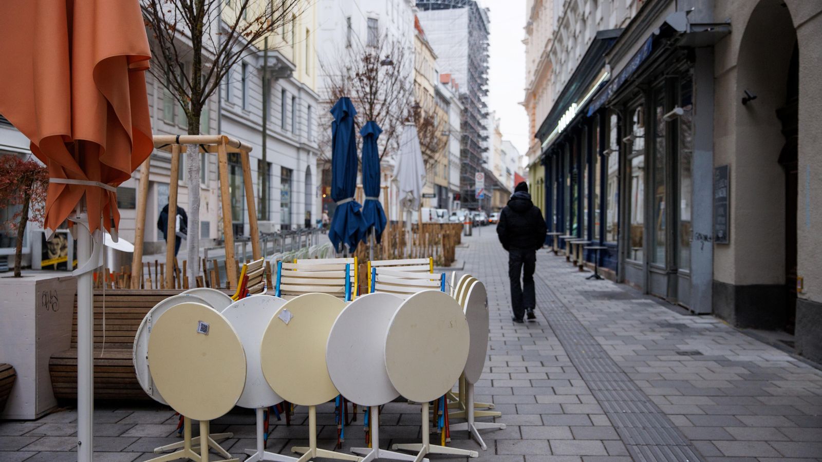 Una persona camina al costat d'un restaurant tancat pel confinament a Viena, Àustria