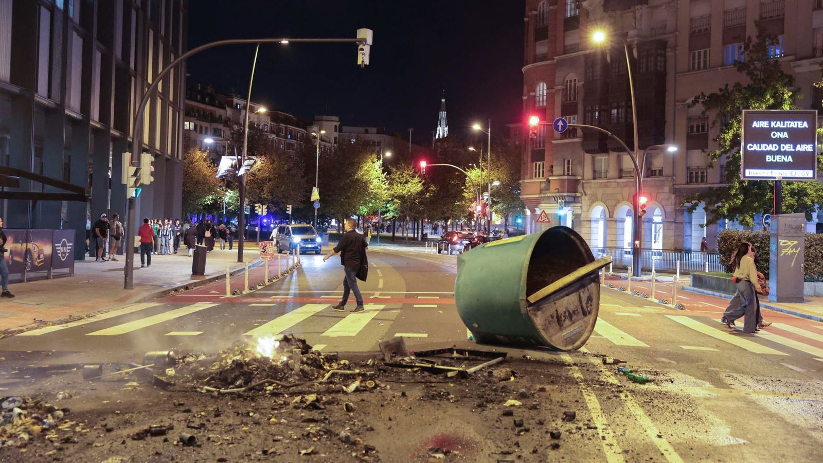 Un dels contenidors bolcats pels grups violents, junt a les restes de mobiliari urbà cremat
