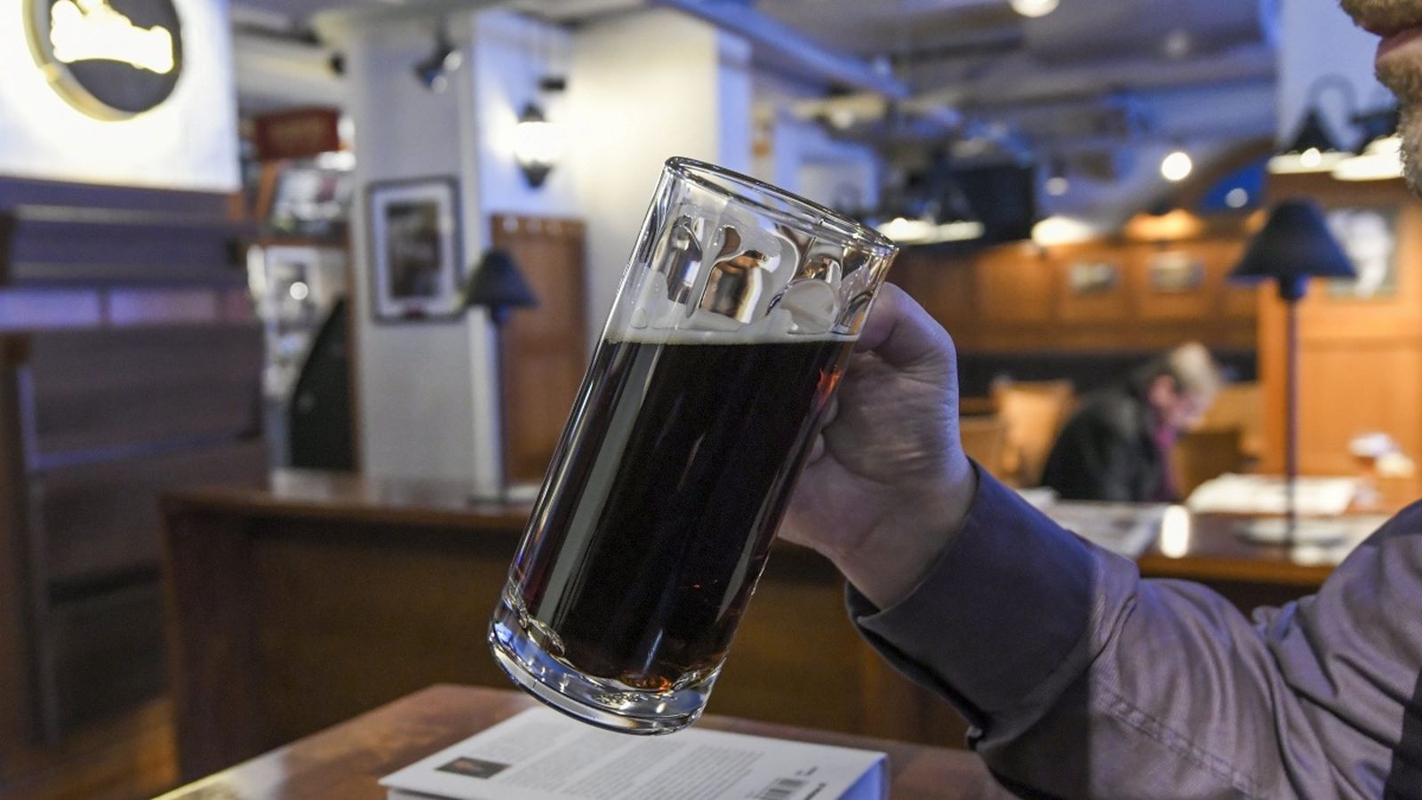 Un home sosté un pitxer de cervesa a un pub, en una imatge d'arxiu