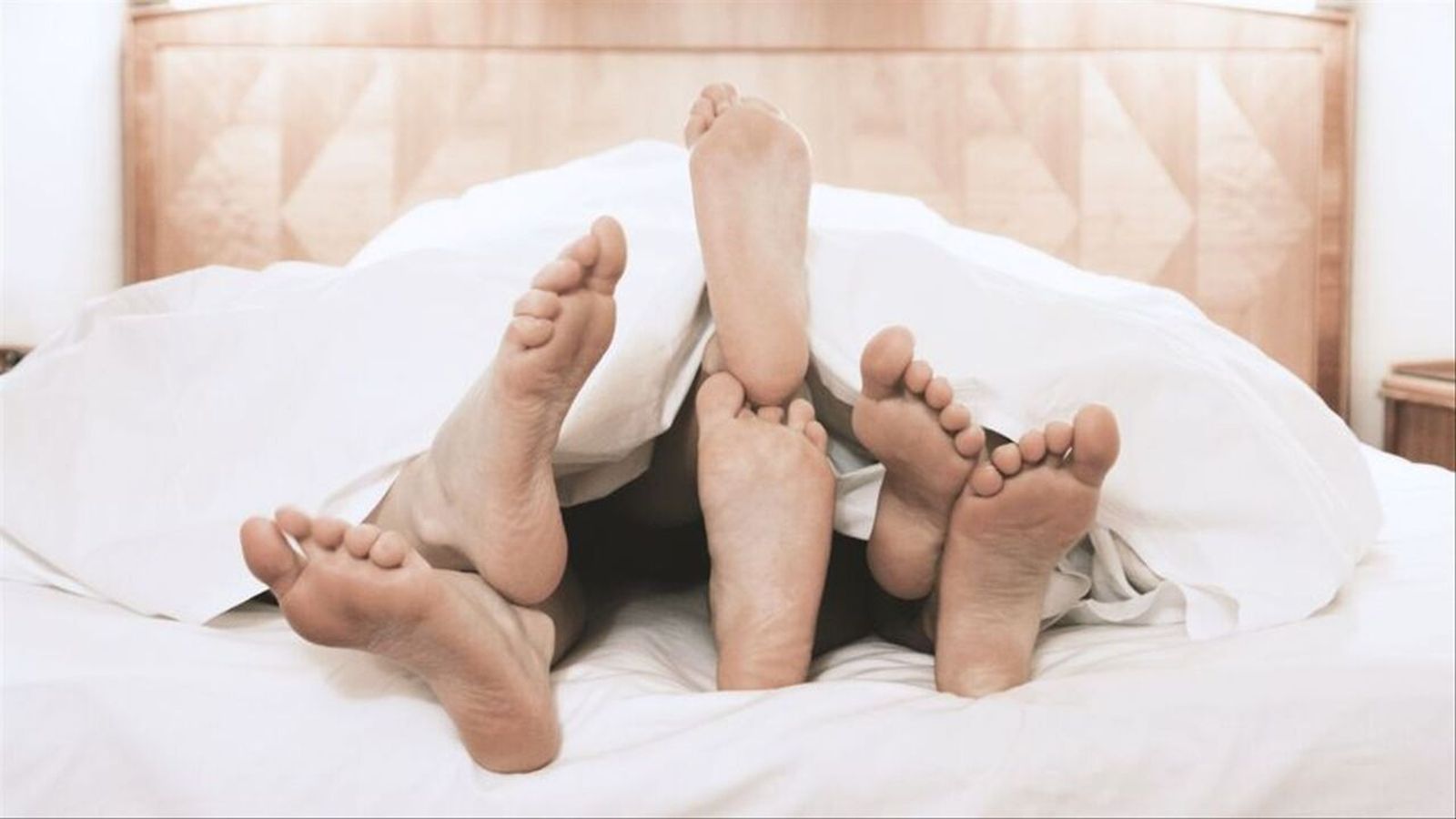 Tres persones juntes en un llit