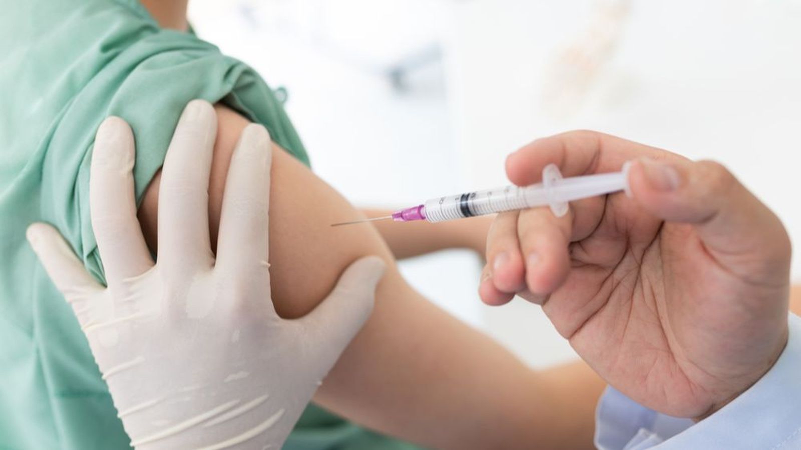 Un professional sanitari injecta una vacuna a un xiquet