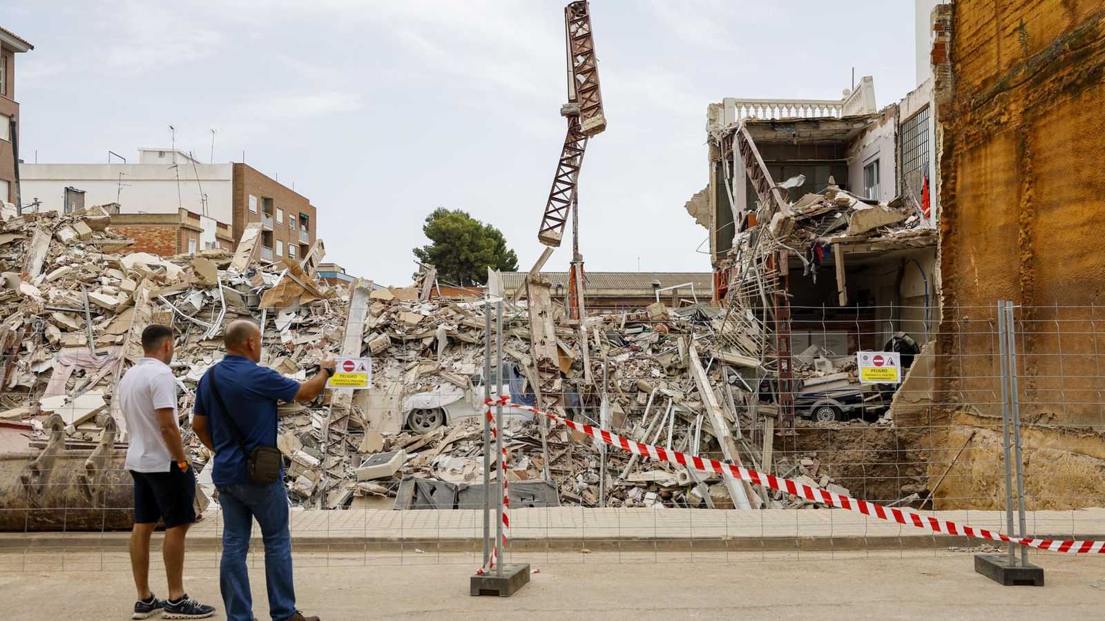 Dos veïns observen les restesd e l'edifici del carrer Las Américas