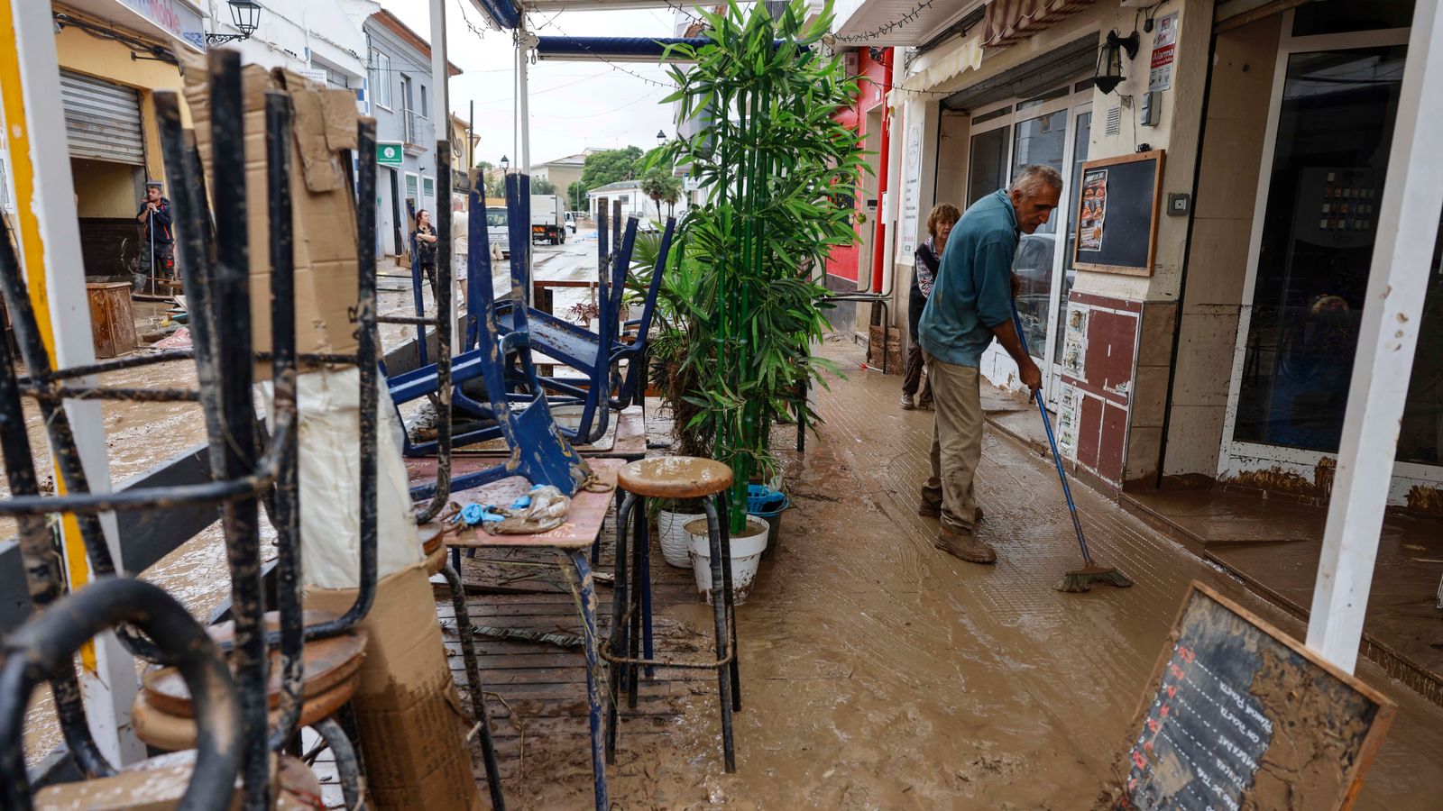Diverses persones lleven el fang dels carrers mentre s'acumula el mobiliari que han hagut de traure a causa de les inundacions