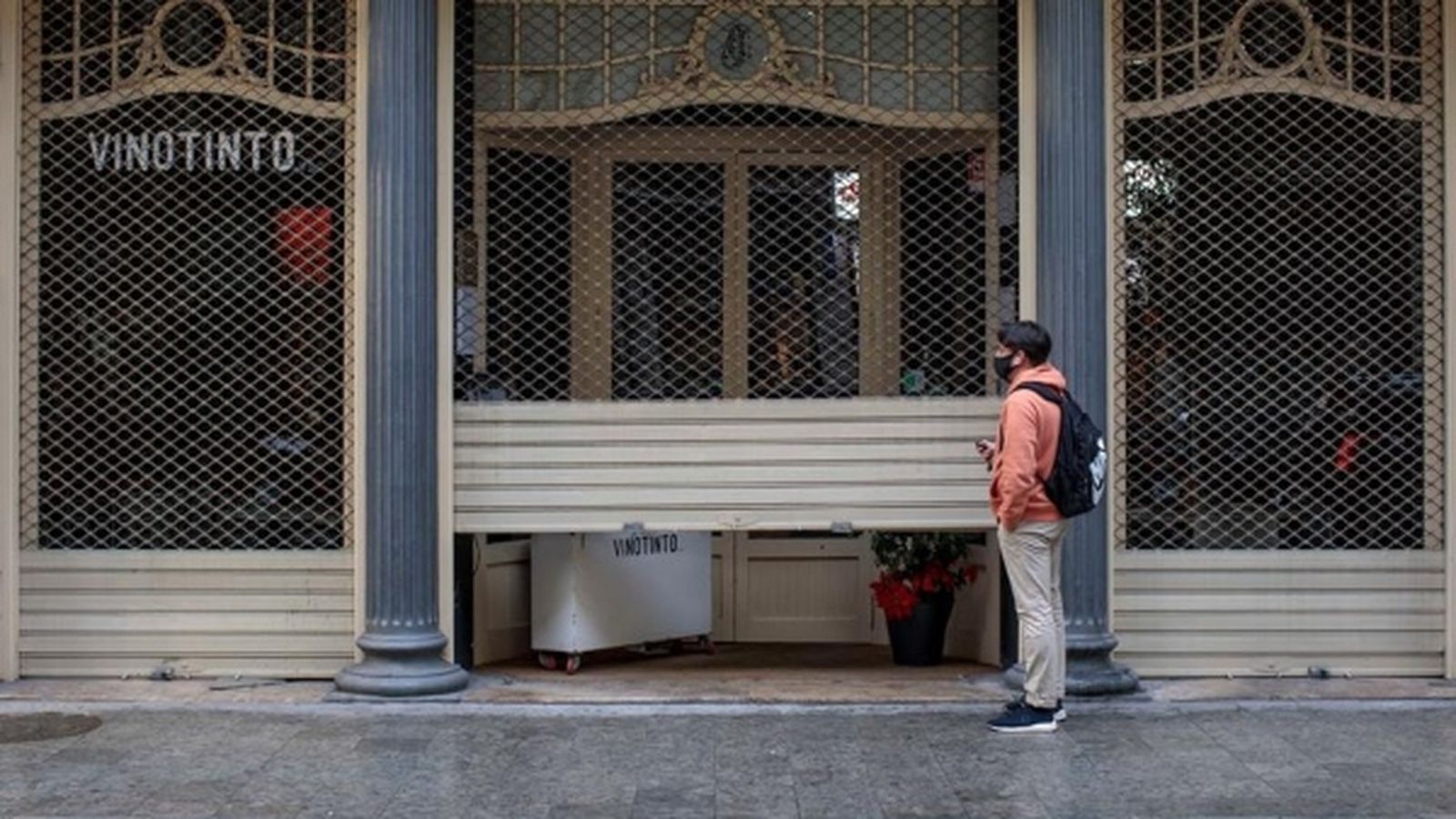 Un treballador d'un restaurant del centre de València baixa la persiana del local