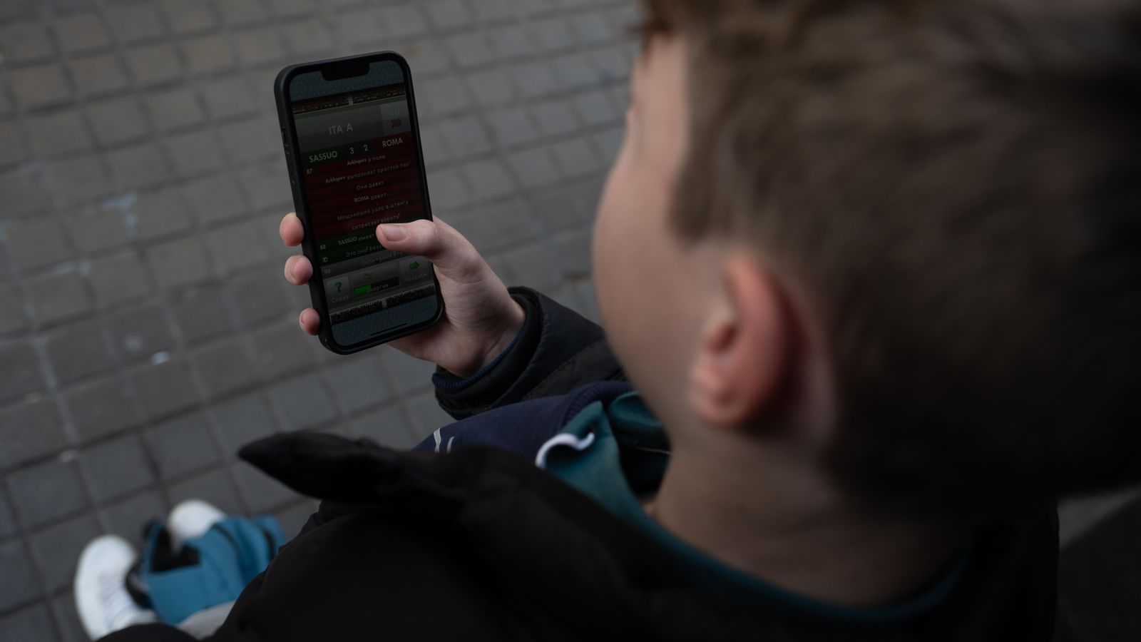 Un xiquet mira el seu telèfon mòbil