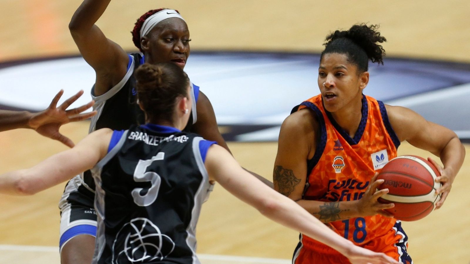 La taronja Celeste Trahan-Davis manté el baló davant de la defensa de dues jugadores de l'IDK
