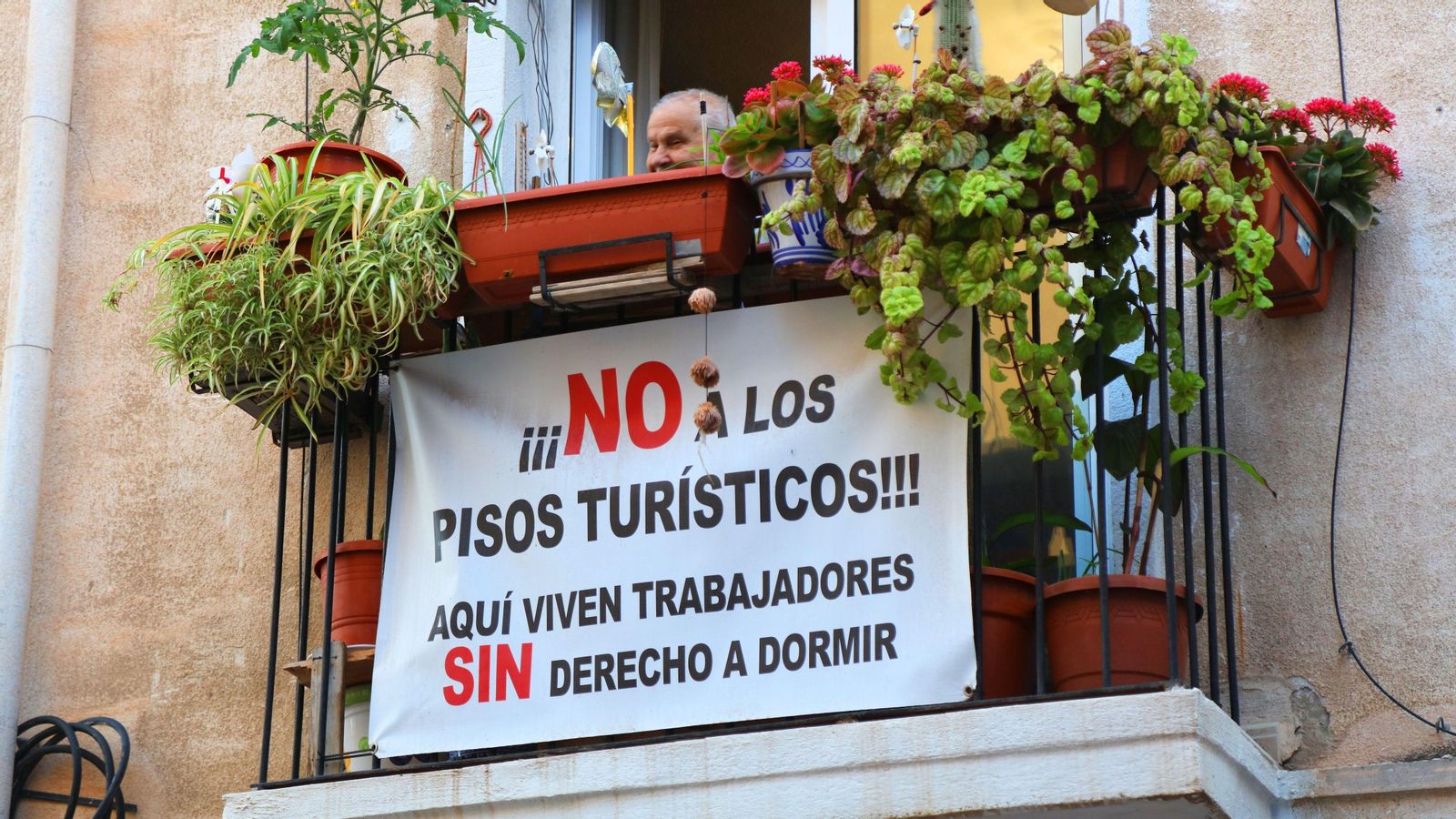 Un cartell contra els apartaments turístics penja d'un balcó d'Alacant