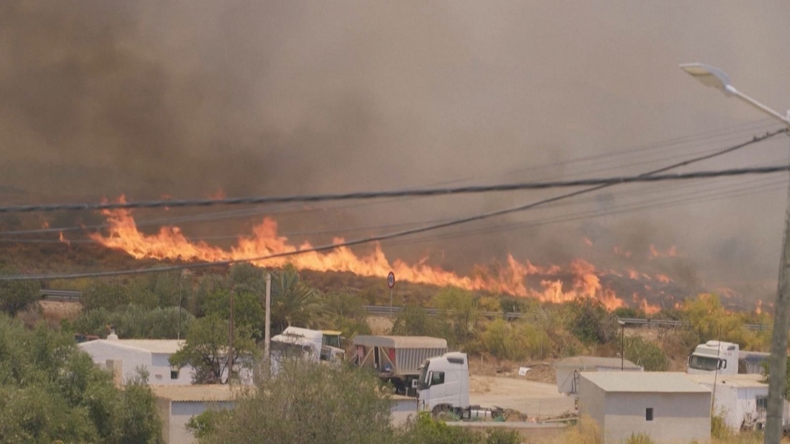 Dos efectius avancen per una carretera prop de les flames de l'incendi de Los Gallardos