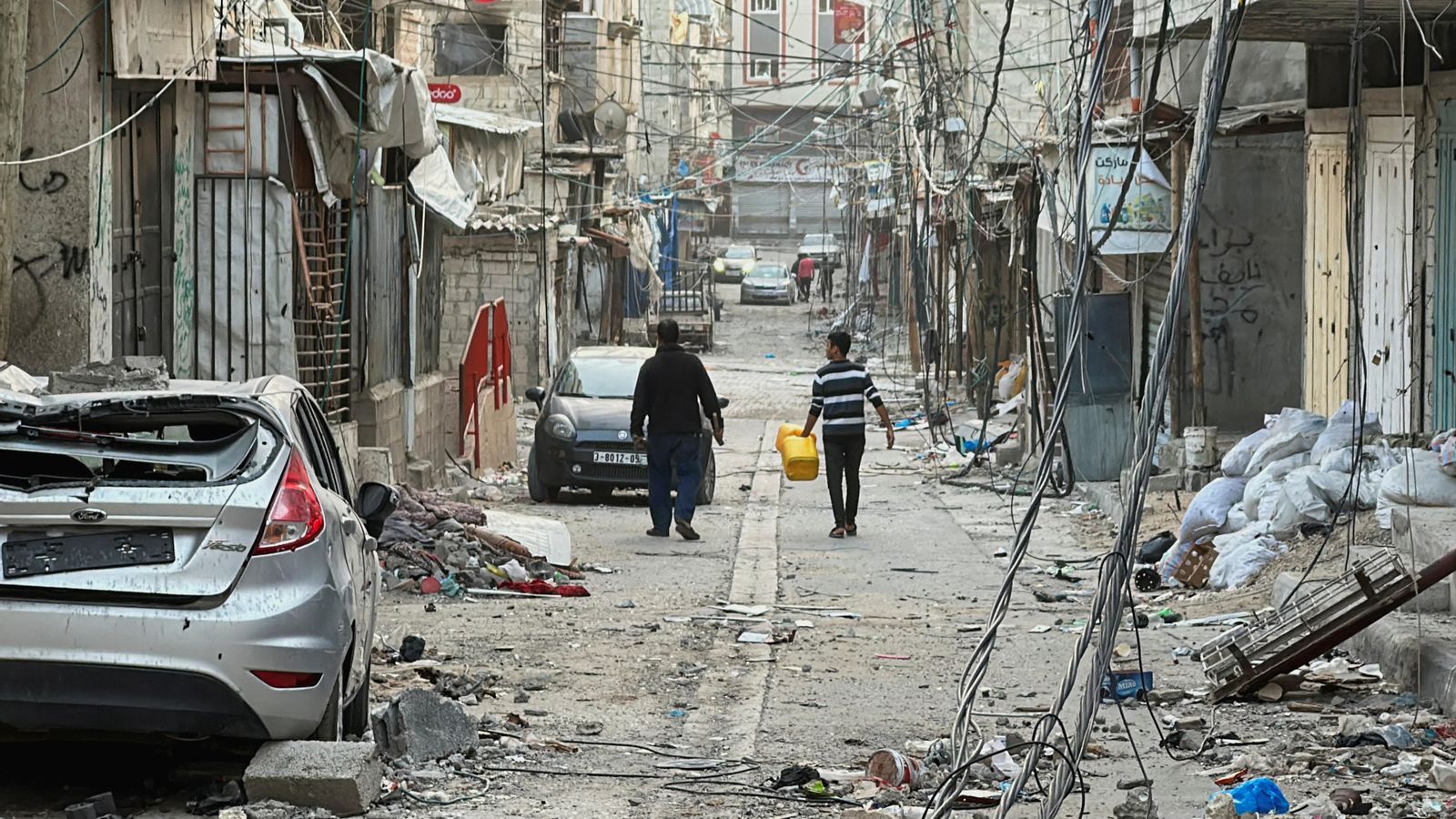 Dues persones caminen durant la treva pel que queda del camp de refugiats de Beach, destruït durant els atacs israelians