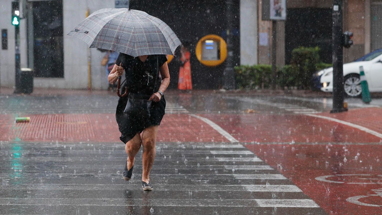 Una dona es protegeix amb un paraigua de la pluja a València
