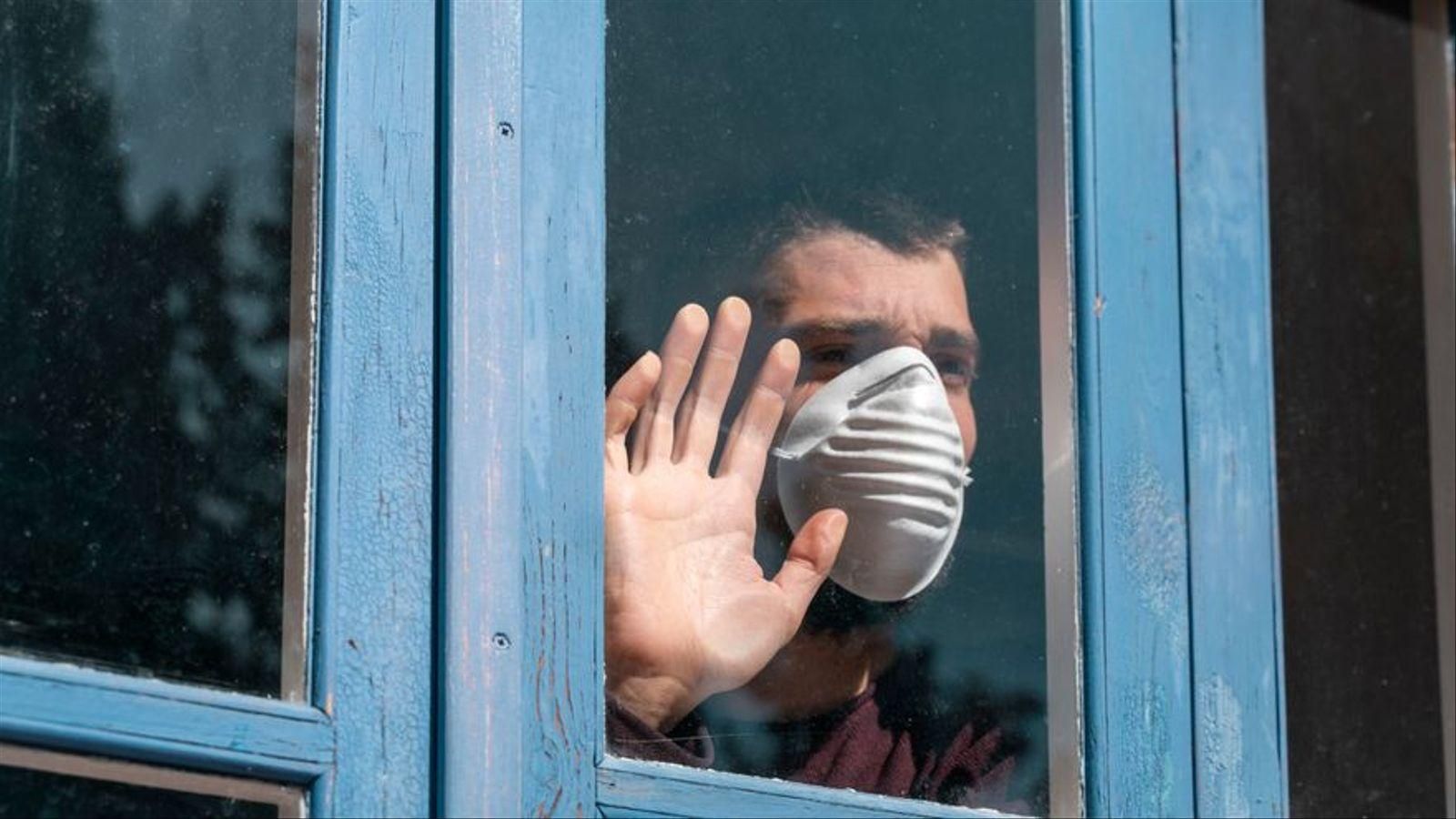 Un home confinat mira per la finestra, imatge d'arxiu