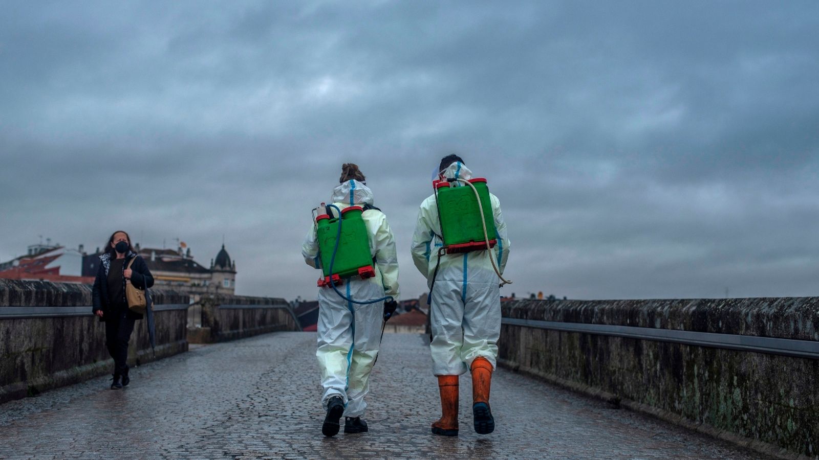 Dos treballadors municipals encarregats de les tasques de desinfecció creuen el Pont Romà d’Ourense