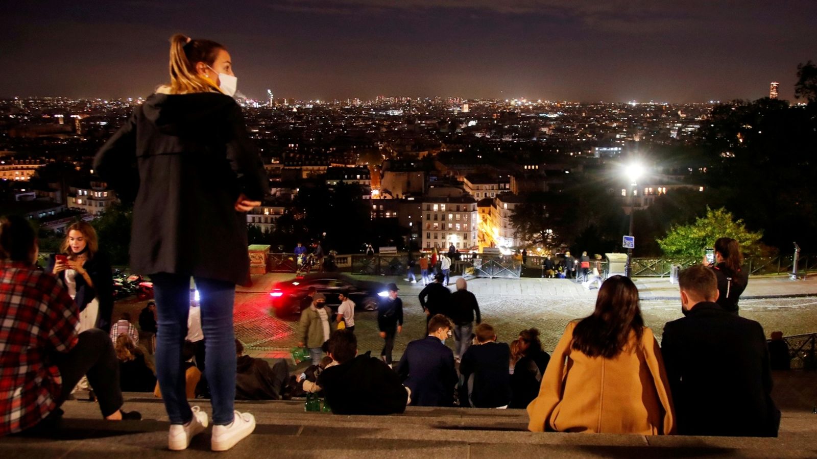 Diverses persones gaudeixen de les vistes de Montmartre, a París, minuts abans del toc de queda