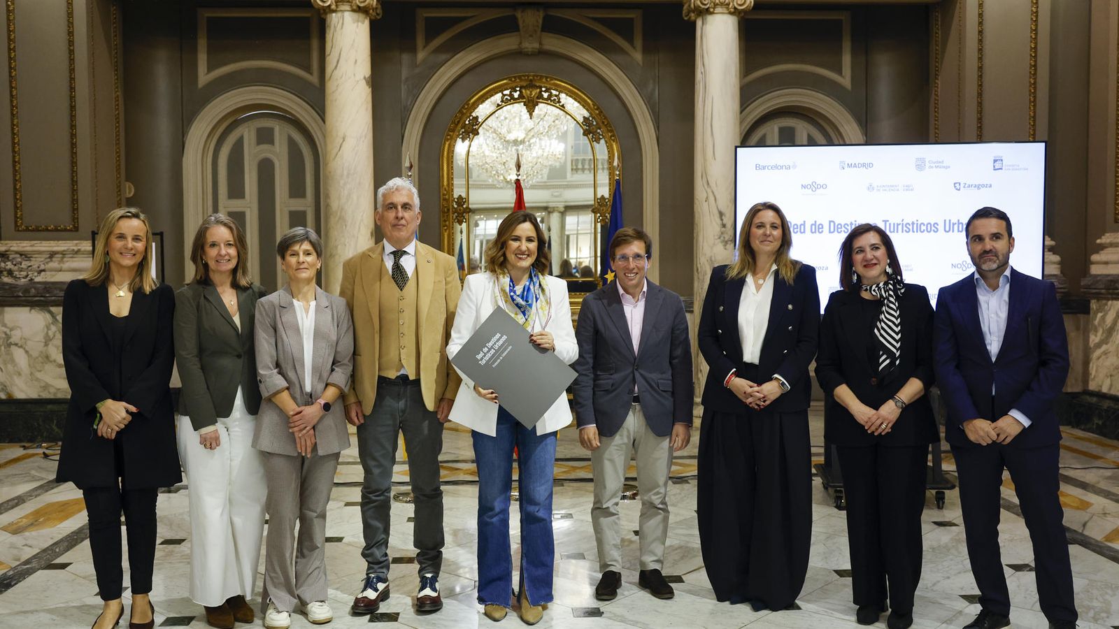L'alcaldessa de València, María José Catalá, i l'alcalde de Madrid, José Luis Martínez Almeida, durant l'acte de la firma, juntament amb representants dels ajuntaments de Barcelona, Màlaga, Sant Sebastià, Sevilla i Saragossa, del protocol per a la creació de la Xarxa de Destinacions Turístiques Urbanes.