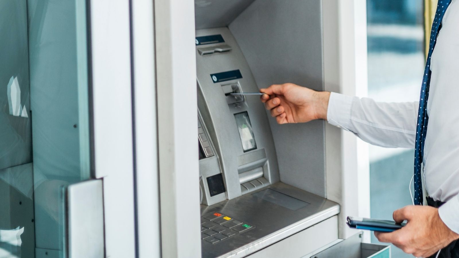 Una persona treu diners d'un caixer