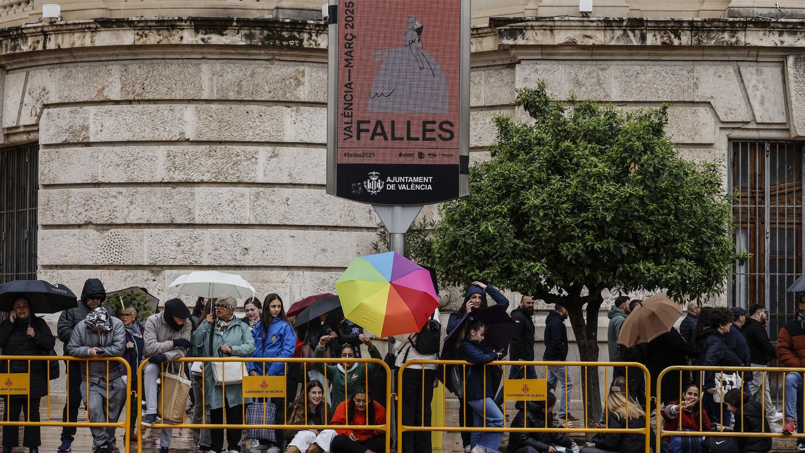 Els assistents a les Falles es protegeixen de la pluja amb paraigües