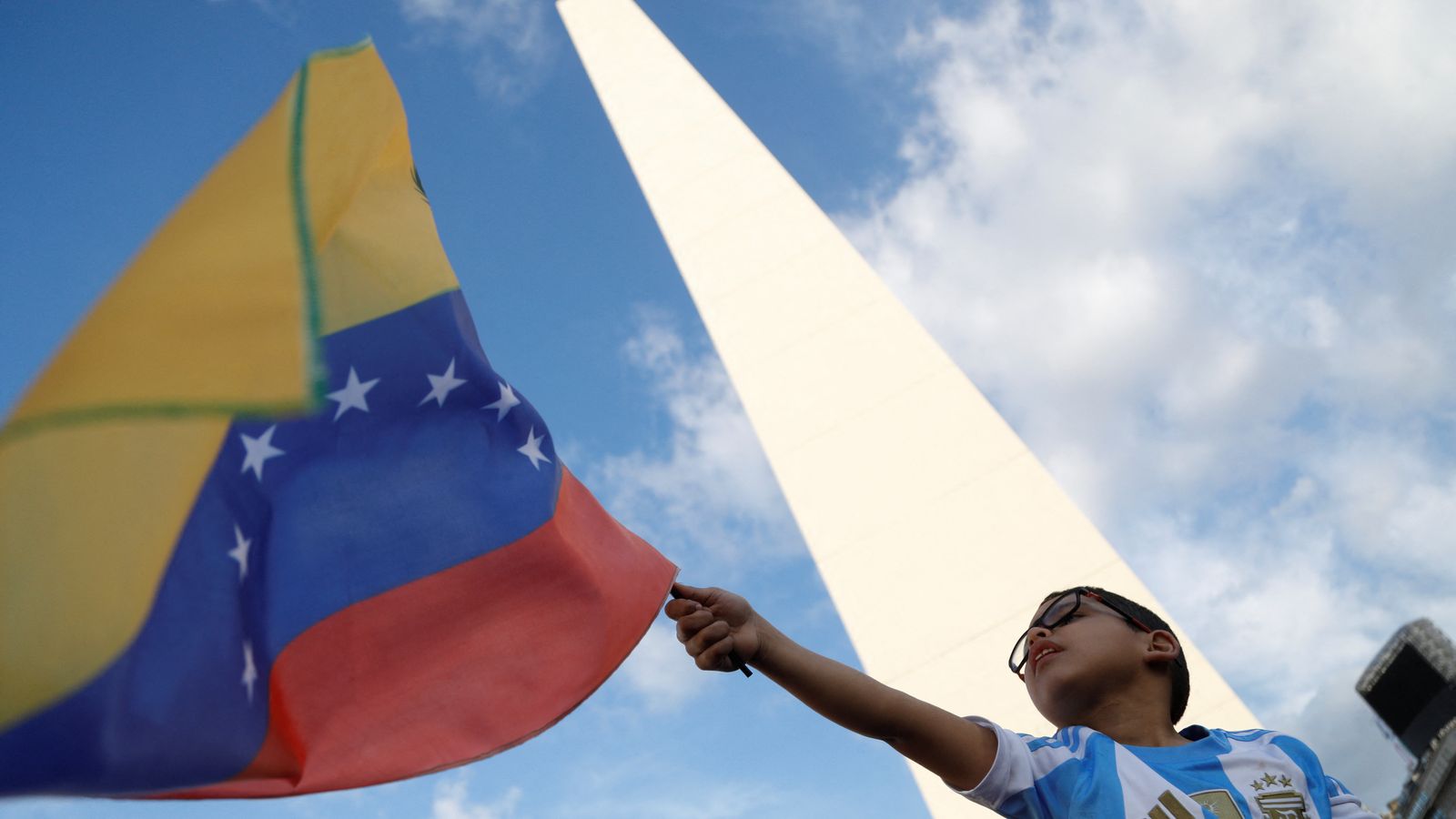 Un nen veneçolà aixeca una bandera durant una manifestació a l'Obelisc per donar suport al candidat opositor de Veneçuela, Edmundo González, a Buenos Aires, Argentina