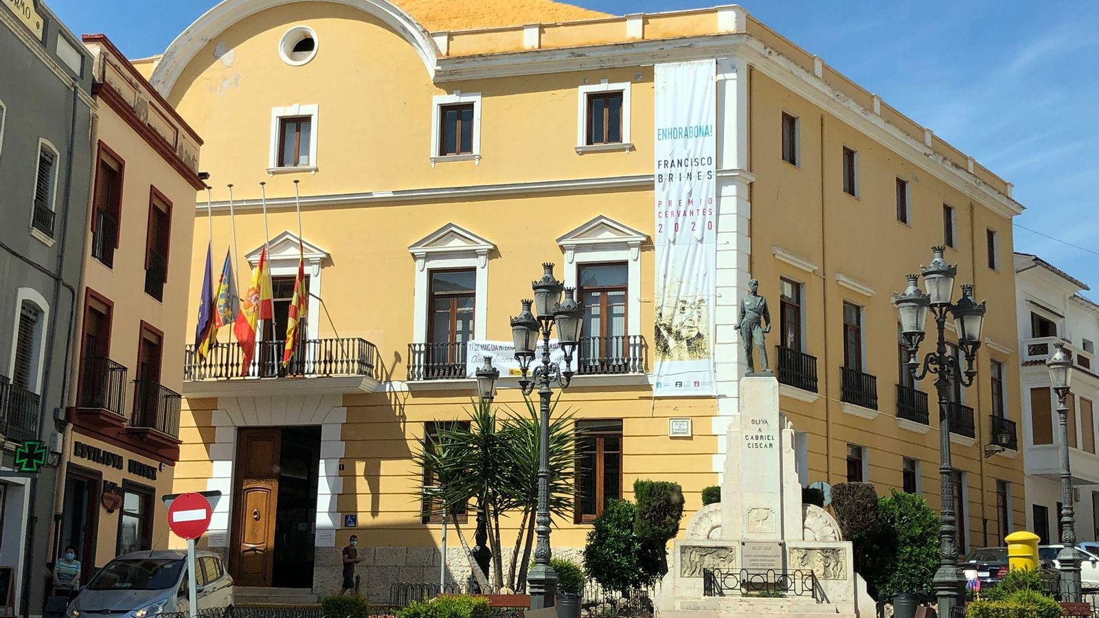 Façana de l'Ajuntament d'Oliva, amb les banderes onejant a mig pal, en senyal de dol